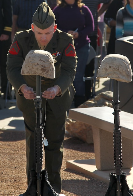 A Marine with 3rd Light Armored Reconnaissance Battalion places a dog tag on one of the military crosses dedicated to the Marines and sailors who fell during Desert Storm and Operation Iraqi Freedom Dec. 7, during the opening of Fallen Hero Memorial Park. There were 25 Marines honored at the opening ceremony with battlefield crosses representing them.