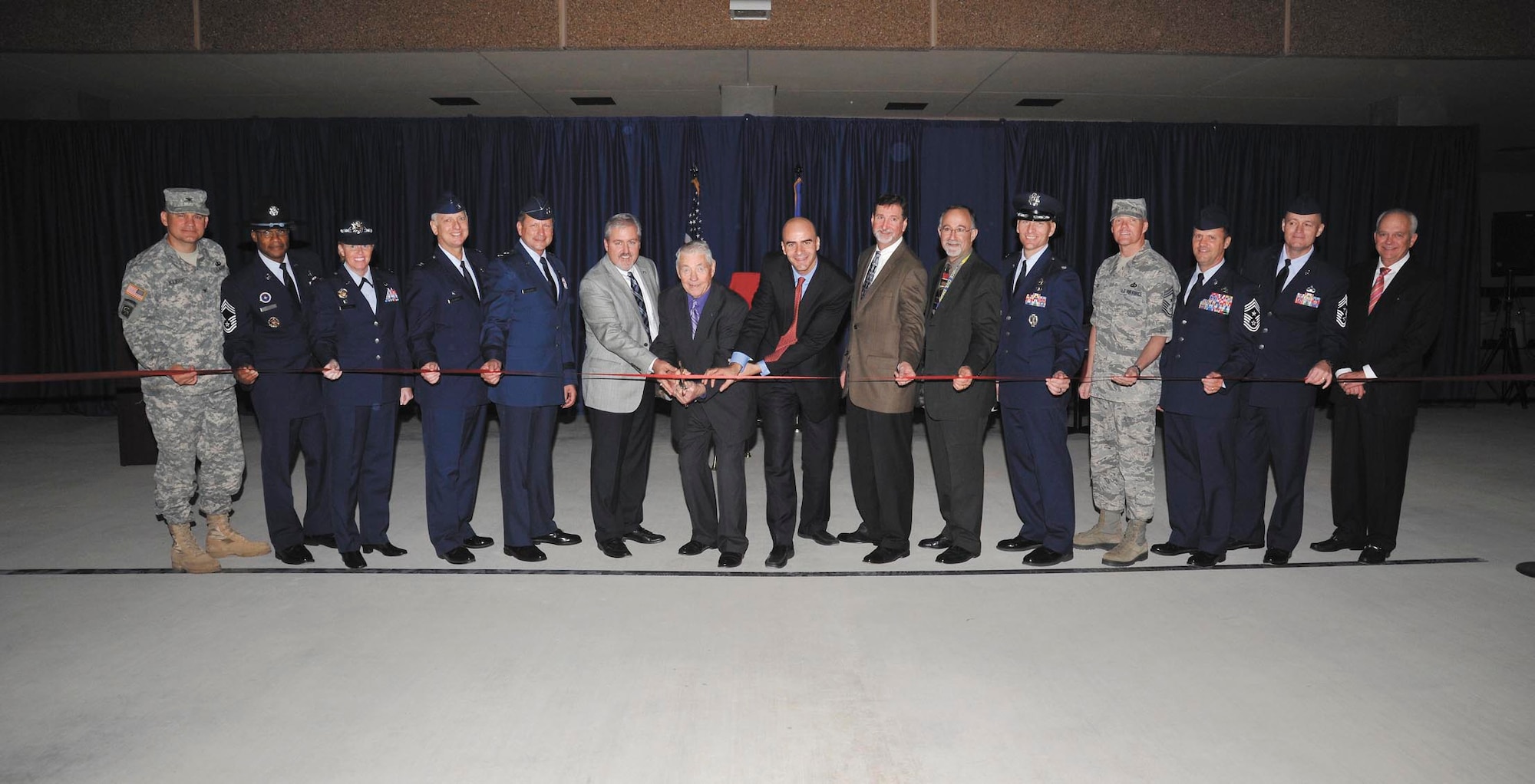 Retired Chief Master Sgt. Robert Gaylor, the fifth chief master sergeant of the Air Force (with scissors) and keynote speaker for the event, along with senior leaders, members of Richard Etchberger’s family and construction officials get ready to cut the ribbon to open the Airman Training Complex #1. (US Air Force Photo by Mr. Alan Boedeker)