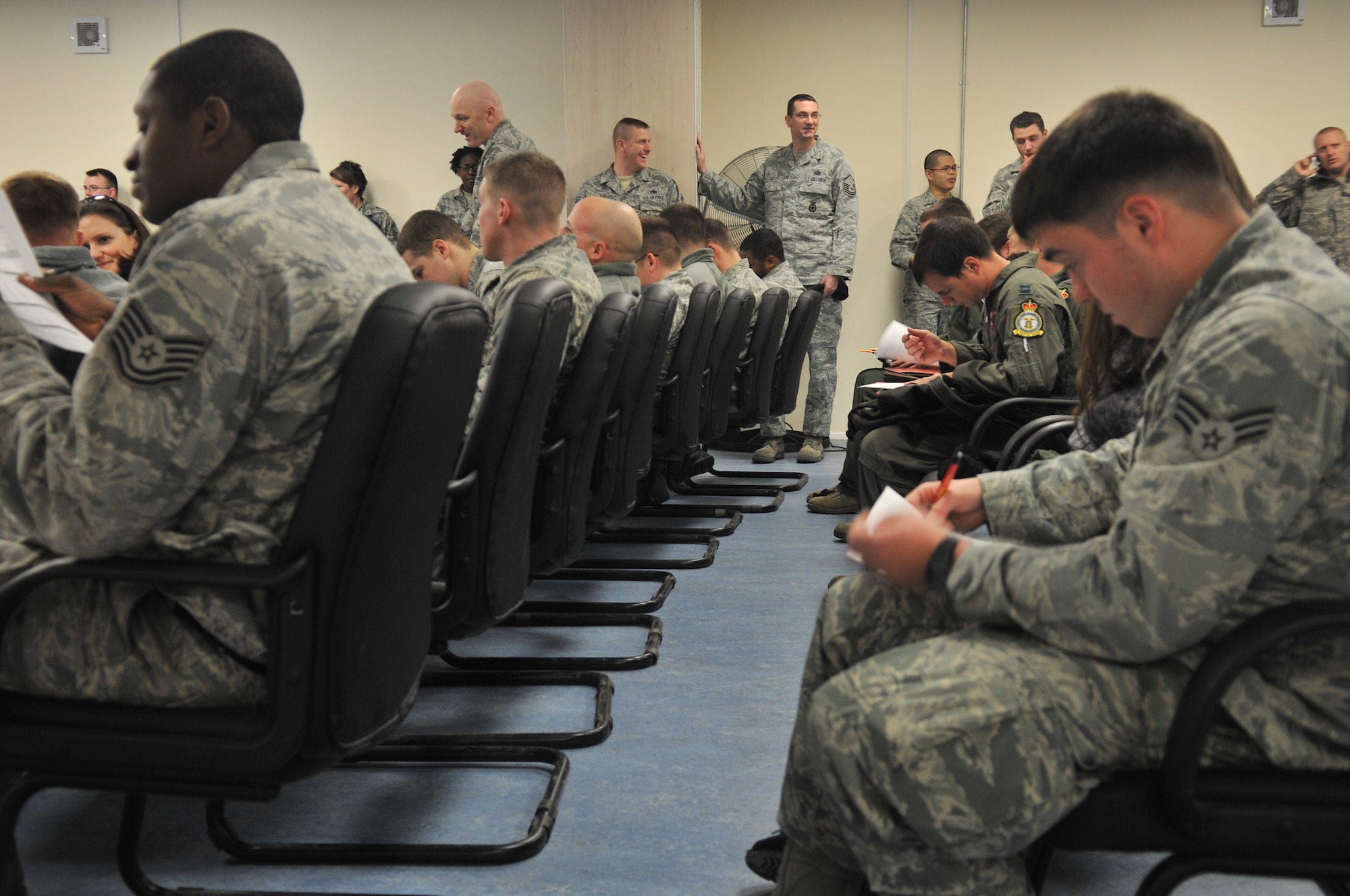 Airmen fill out paperwork Dec. 17, 2012, at RAF Mildenhall, England, after returning from a deployment. A reintegration briefing was the first stop in inprocessing to the base. (U.S. Air Force photo by Airman 1st Class Dillon Johnston/Released)