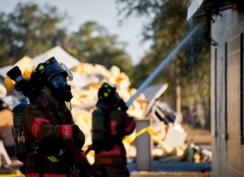 A firefighter eyes the corner of a building as another sprays down an additional side of the roof during a structural live-fire training exercise at Eglin Air Force Base, Fla., Dec. 13. The building used for the training was scheduled to be demolished Dec. 19. (U.S. Air Force photo/Samuel King Jr.)
