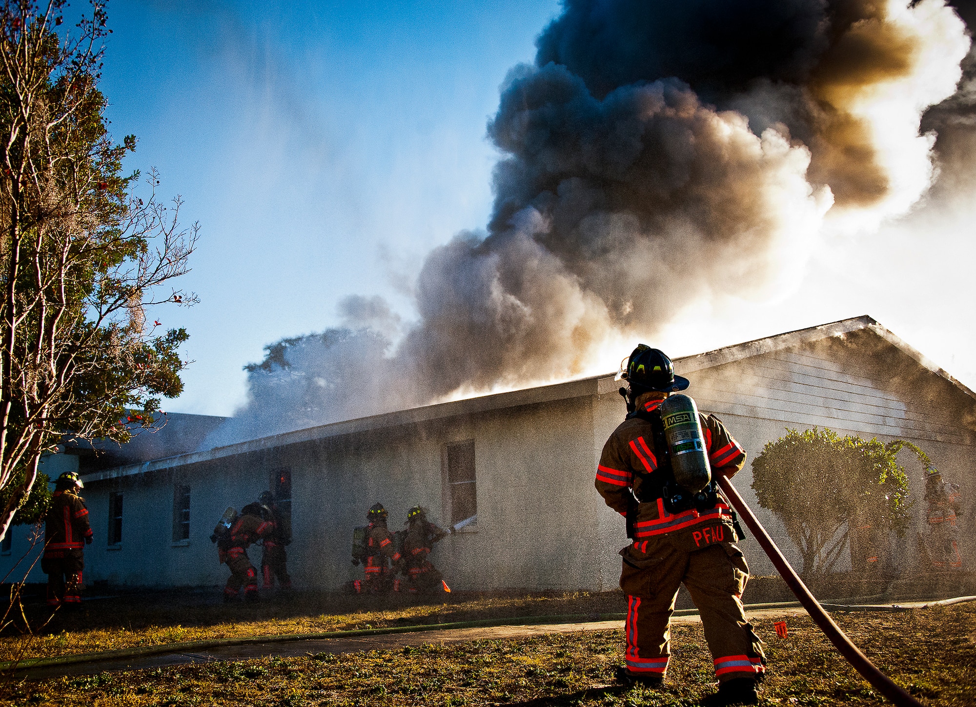 Firefighters move in to battle a blaze inside a building as water mists down on them from a fire truck during a live-fire training exercise at Eglin Air Force Base, Fla., Dec. 13.  The building used for the training was scheduled to be demolished Dec. 19. (U.S. Air Force photo/Samuel King Jr.)