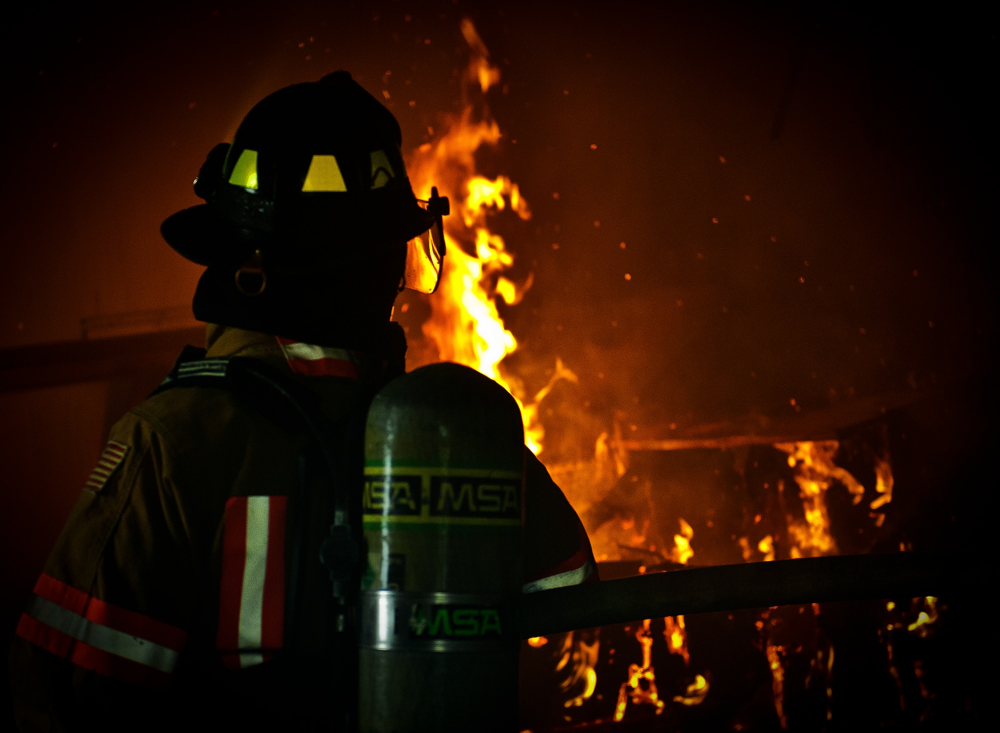 A firefighter watches the blaze during a structural live-fire training scenario at Eglin Air Force Base, Fla., Dec. 12.  Two-person teams entered a building on fire and demonstrated hose and various firefighting procedures while engaging the controlled blaze.  (U.S. Air Force photo/Samuel King Jr.)