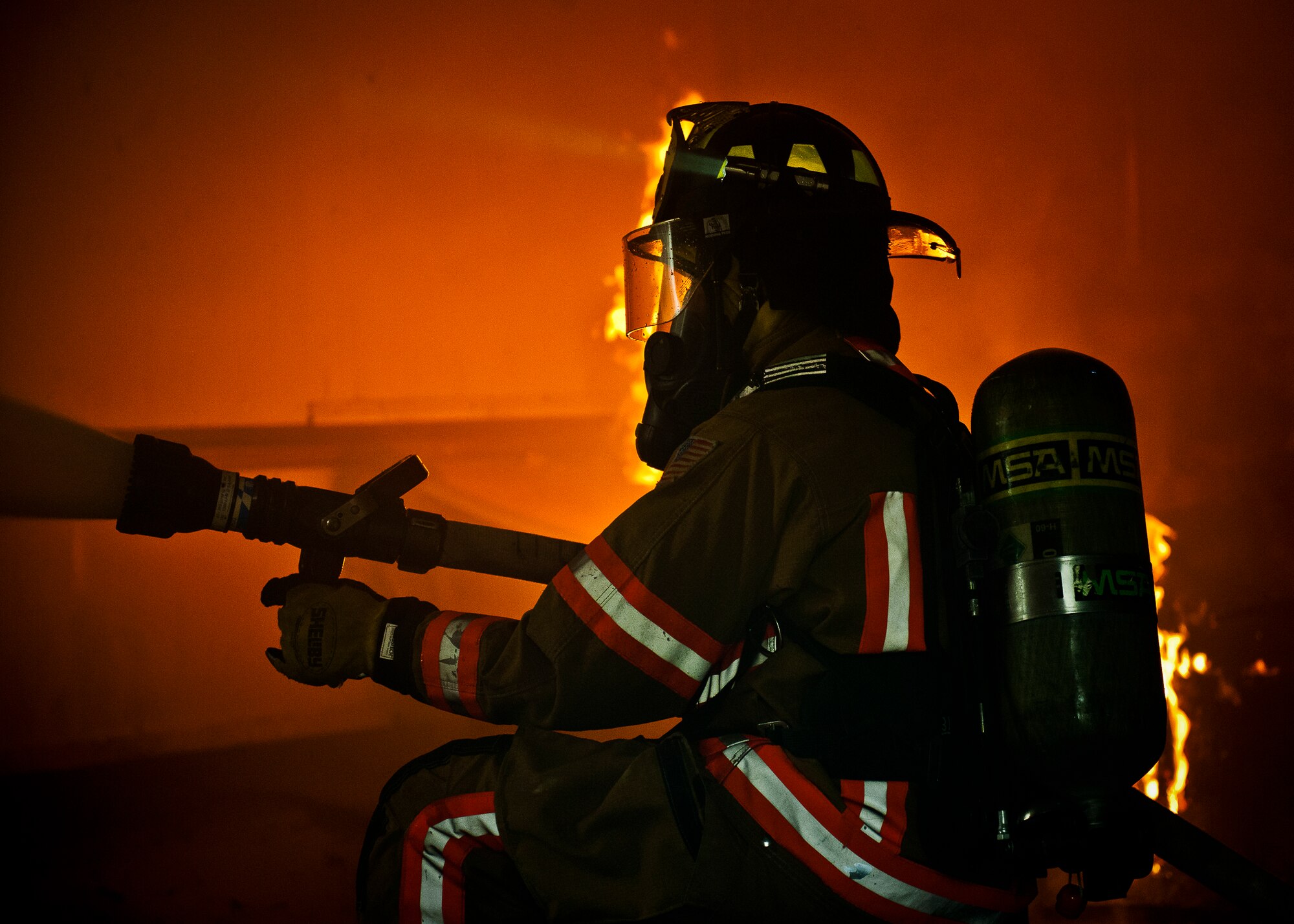 Airman 1st Class Micah Moody, a firefighter with the 96th Civil Engineer Squadron, sprays water out of a window to help ventilate the smoke from the room during a structural live-fire training scenario at Eglin Air Force Base, Fla., Dec. 12.  Two-person teams entered a building on fire and demonstrated hose and various firefighting procedures while engaging the controlled blaze.  (U.S. Air Force photo/Samuel King Jr.)