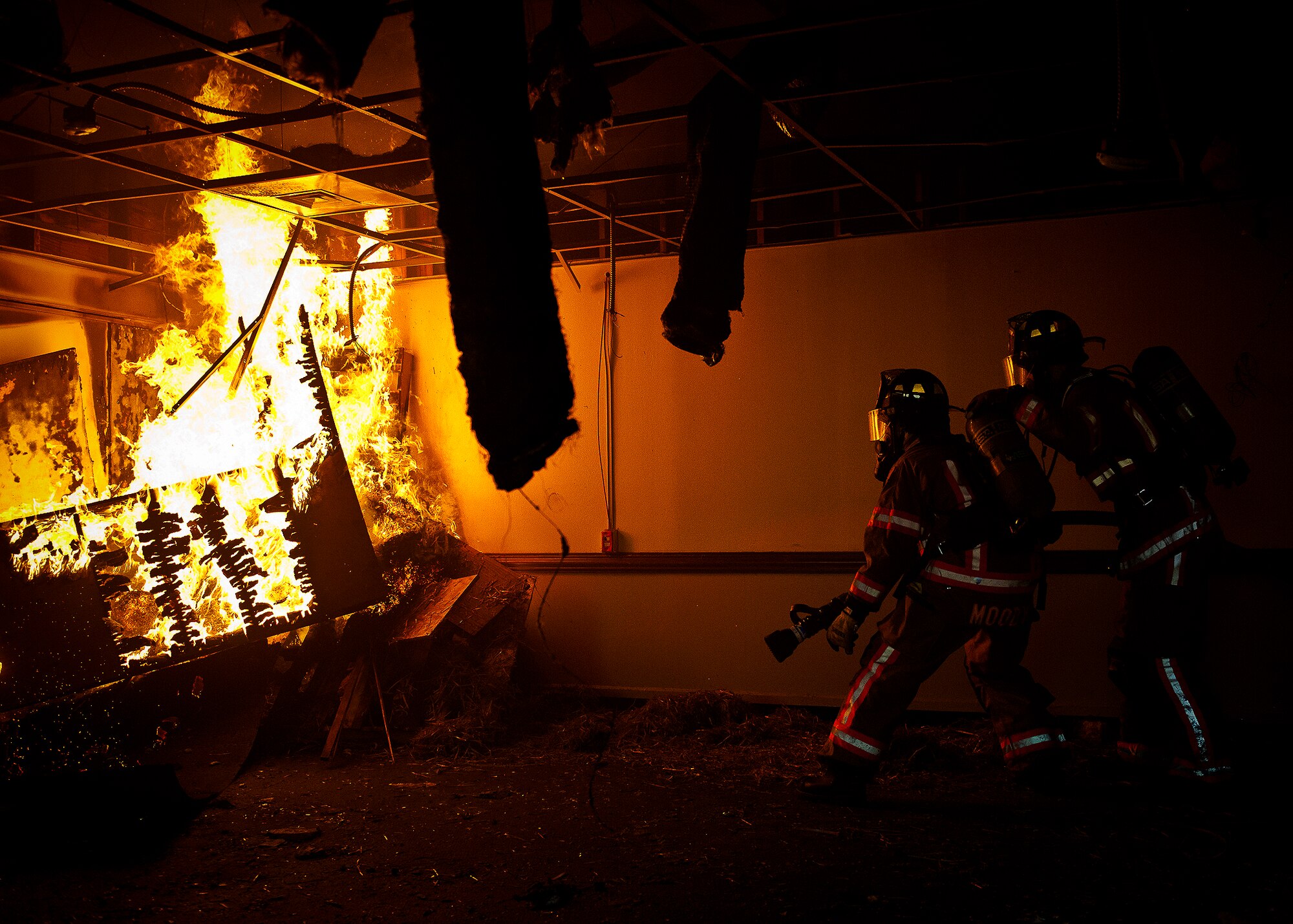 Airman 1st Class Micah Moody, a firefighter with the 96th Civil Engineer Squadron, and his partner, move into place to battle the blaze during a structural live-fire training scenario at Eglin Air Force Base, Fla., Dec. 12.  Two-person teams entered a building on fire and demonstrated hose and various firefighting procedures while engaging the controlled blaze.  (U.S. Air Force photo/Samuel King Jr.)