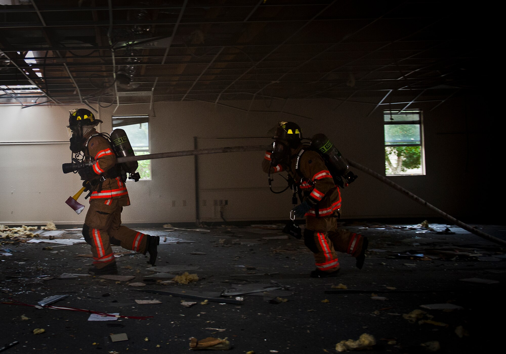 Firefighters enter the building pulling the fire hose and other equipment during a structural live-fire training scenario at Eglin Air Force Base, Fla., Dec. 12.  Two-person teams entered a building on fire and demonstrated hose and various firefighting procedures while engaging the controlled blaze.  (U.S. Air Force photo/Samuel King Jr.)