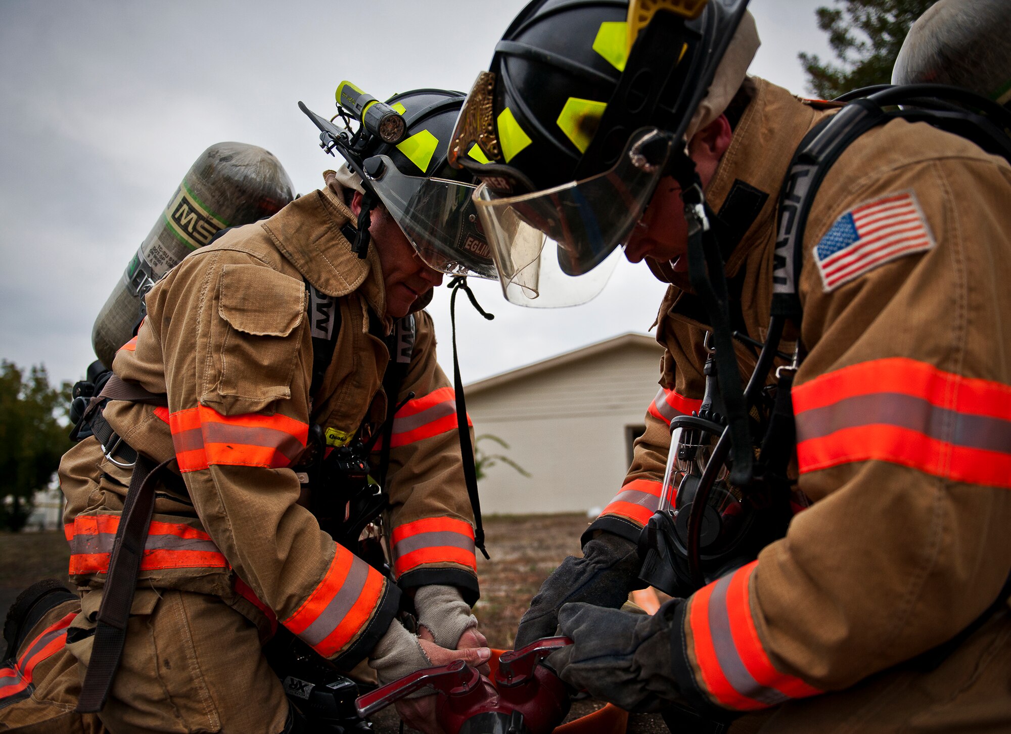Firefighters connect and open the valves to bring the water to the hoses during a structural live-fire training scenario at Eglin Air Force Base, Fla., Dec. 12.  Two-person teams entered a building on fire and demonstrated hose and various firefighting procedures while engaging the controlled blaze.  (U.S. Air Force photo/Samuel King Jr.)