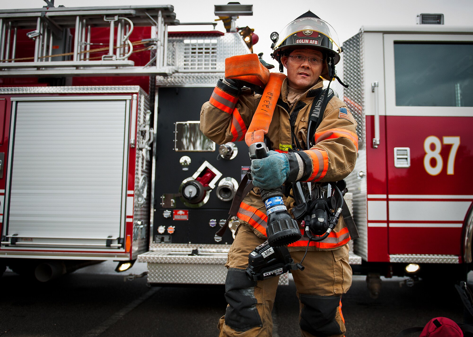 Kevin Anderson, a captain with the 96th Civil Engineer Squadron, pulls a hose down from Fire Engine 87 during the structural live-fire training scenario at Eglin Air Force Base, Fla., Dec. 12.  Two-person teams entered a building on fire and demonstrated hose and various firefighting procedures while engaging the controlled blaze.  (U.S. Air Force photo/Samuel King Jr.)