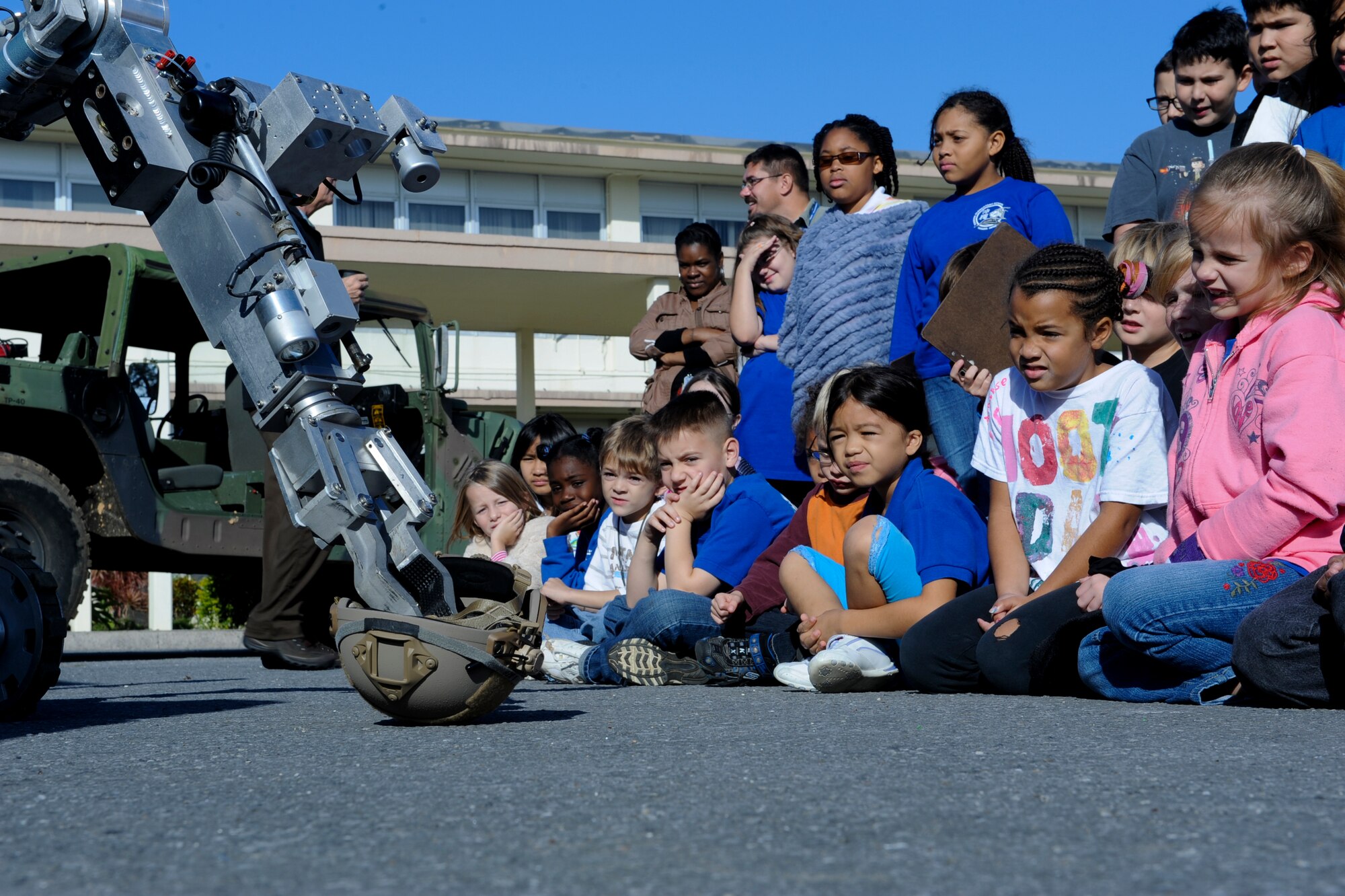 Kadena Elementary School students watch as a Remotec ANDROS F-6A explosive ordinance disposal robot prepares to pick up a helmet during an EOD demonstration on Kadena Air Base, Japan, Dec. 14, 2012. The robot can take a person?s place during EOD, reconnaissance, special weapons and tactics and other hazardous missions instead of having a casualty you would send the robot in. The second grade students are studying robotics in support of Department of Defense Education Activity?s initiative of the science, technology, engineering and math program. (U.S. Air Force photo/Airman 1st Class Justin Veazie)