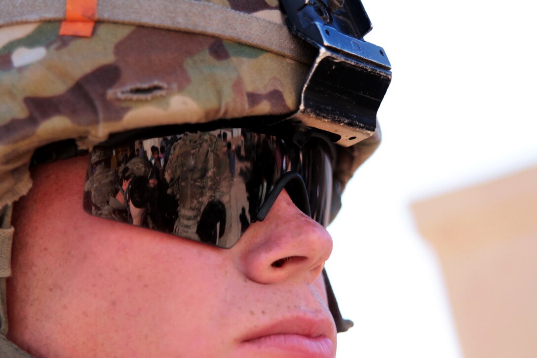 U.S. troops and local Afghans are reflected in the sunglasses of U.S. Army Spc. Jacob Bobbe during a key leader engagement in the Lash-e Juwayn district in Afghanistan's Farah province, Dec. 11, 2012. Bobbe is assigned to Provincial Reconstruction Team Farah.