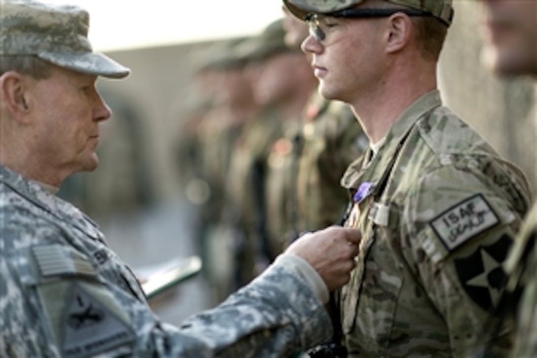 U.S. Army Gen Martin E. Dempsey, left, chairman of the Joint Chiefs of Staff, presents a Purple Heart medal to a U.S. service members on Forward Operating Base Azim Jan Karez, Afghanistan, Dec. 16, 2012.  