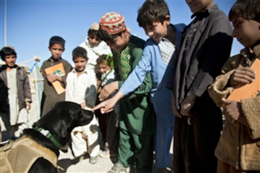 Paris, a coalition force military working dog, shows his gentler side as he interacts with children in a village in Farah province, Afghanistan, Dec. 11, 2012.