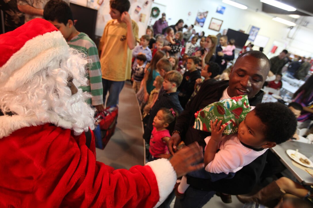 Sgt. Adrian Richards, food service specialist with the Command Element, 31st Marine Expeditionary Unit, and his daughter, receive a present from Santa during the Command Element Christmas party here, Dec. 14. Prior to the holiday leave period, the Command Element service members and their families came together for a home-cooked holiday meal and to treat their children to a visit from Santa Claus. The 31st MEU is the only continuously forward-deployed MEU and is the Marine Corps’ force in readiness in the Asia-Pacific region.