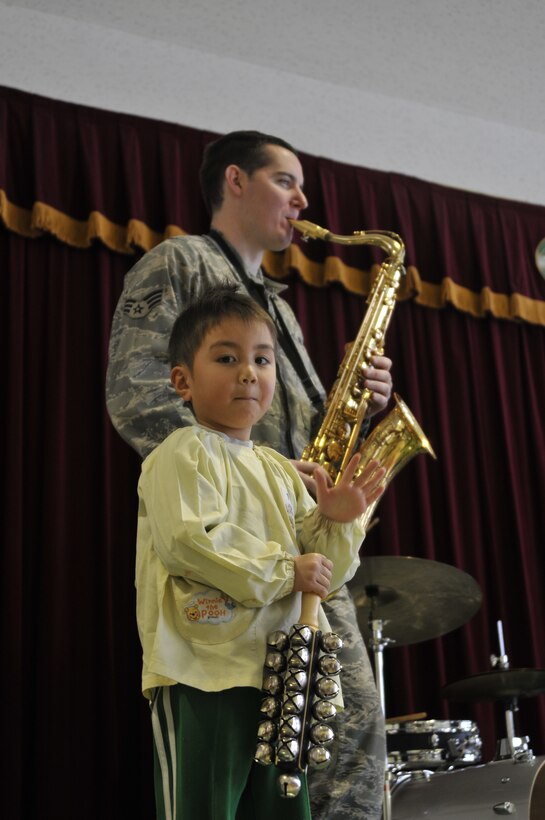 MISAWA, Japan -- Senior Airman Greg Pflugh, Band of the Pacific-Asia saxophonist, background, performs a solo while a preschool student plays “Jingle Bells” during a performance by the USAF Band of the Pacific-Asia at the Misawa Municipal First Preschool, Misawa, Japan on Dec. 11, 2012.  The group performed 13 shows for over 1,000 listeners from children to US and Japanese military personnel while improving international relations and spreading holiday cheer. (US Air Force Photo/Tech. Sgt. Phillip Butterfield)