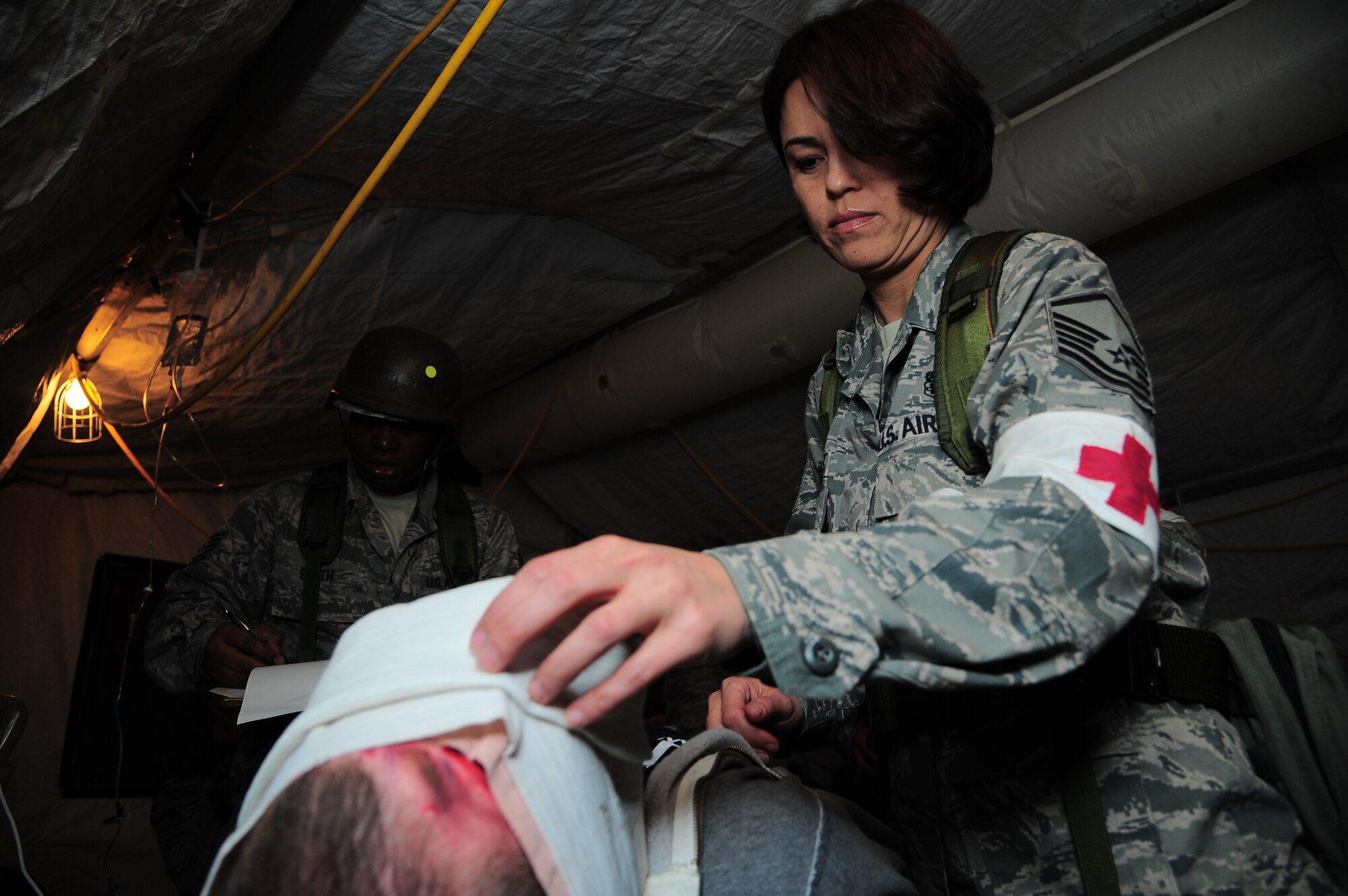 U.S. Air Force Master Sgt. Joy Flumerfelt, 4th Medical Support Squadron independent duty medic, assesses a wound during Operational Readiness Exercise Coronet Warrior 12-06, at a simulated deployed location on Seymour Johnson Air Force Base, N.C., Dec. 18, 2012. Medical staff deliver additional treatment after self aid buddy care has been performed in the field. (U.S. Air Force photo/Airman 1st Class Aubrey White/Released)