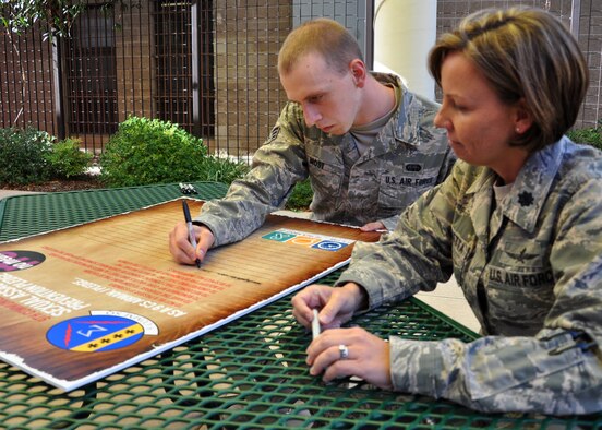 U.S. Air Force Senior Airman Zack Most and Lt. Col. Susan Magaletta, 9th Communications Squadron, become the first Airmen to sign a declaration to end sexual assault Nov. 13, 2012 at Beale Air Force Base, Calif. More than 50 communications Airmen have signed the declaration since then. The document is poster size and will rotate throughout the squadron to remain visible to all Airmen. (U.S. Air Force photo by Airman 1st Class Andrew Buchanan/Released) 
