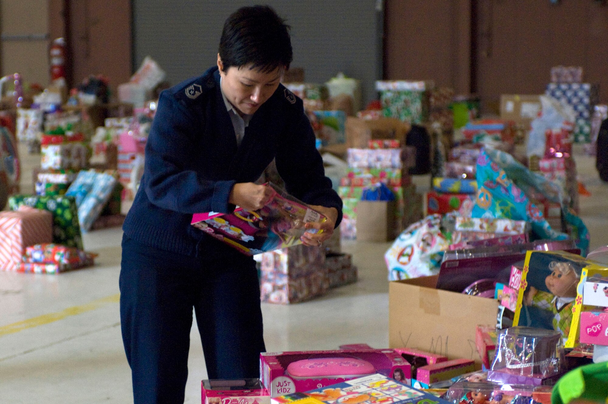 Master Sgt. Susan Rogers, chief of weapons and tactics at the 526th Intelligence Group, places gifts in a pile to be sorted and distributed to families of the Nellis and Creech community Dec. 17, 2012 at Nellis Air Force Base, Nev.  Operation Warmheart is a program organized by the first sergeants of Nellis and Creech to provide gifts for families in the community that are in need. (U.S. Air Force photo by Airman 1st Class Monet Villacorte)