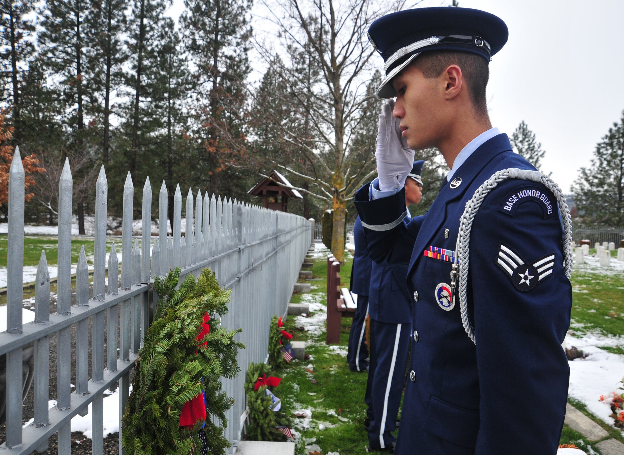 Senior Airman Chankrisna Chim, member of the Fairchild Honor Guard, gives respect to fallen veterans during the Wreaths Across America event at the Fort Wright Cemetery in Spokane, Wash., Dec. 15, 2012. This marks the first year that Wreaths Across America was held at the cemetery. (U.S. Air Force photo by Airman 1st Class Taylor Curry)