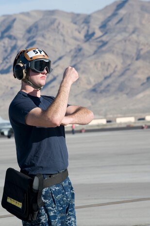 Seaman Trevor Stratton, Electronic Attack Squadron 138 plane captain, marshals an EA-18G Growler during the U.S. Air Force Weapons School Mission Employment Phase Dec. 11, 2012, at Nellis Air Force Base, Nev. The exercise is hosted north of Las Vegas on the Nevada Test and Training Range. (U.S. Air Force photo by Senior Airman Matthew Lancaster)