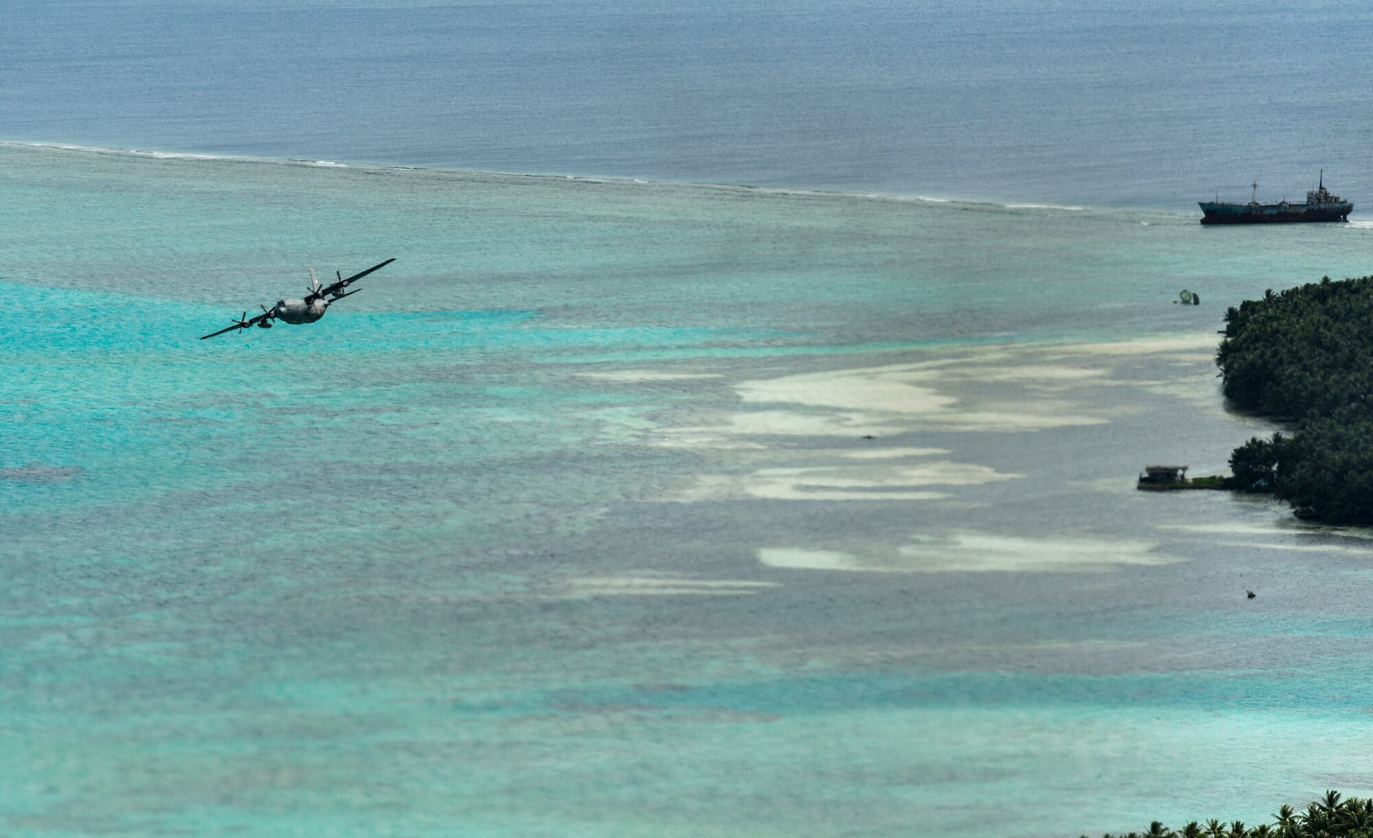 OVER THE PACIFIC OCEAN -- A C-130 Hercules from Yokota Air Base, Japan, makes a low pass off the shore an island in Micronesia Dec. 18, 2012. The flight was part of Operation Christmas Drop, the world's longest-running humanitarian airlift mission. (U.S. Air Force photo by Tech. Sgt. Samuel Morse)