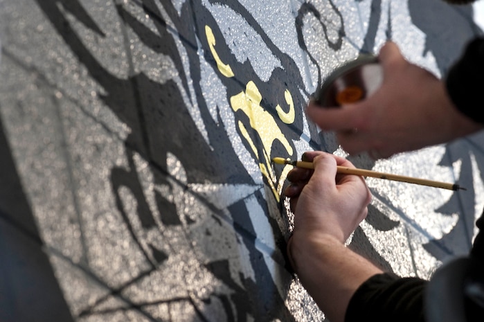 Michael Sullivan, artist and brother of Staff Sgt. Daniel Sullivan, 823rd Maintenance Squadron aircraft structural maintenance craftsman, paints details to the new 823rd MXS unit patch Dec. 15, 2012, at Nellis Air Force Base, Nev. The new patch was designed by Master Sgt. Mark Schultz of the 823rd MXS. (U.S. Air Force photo by Staff Sgt. Christopher Hubenthal)