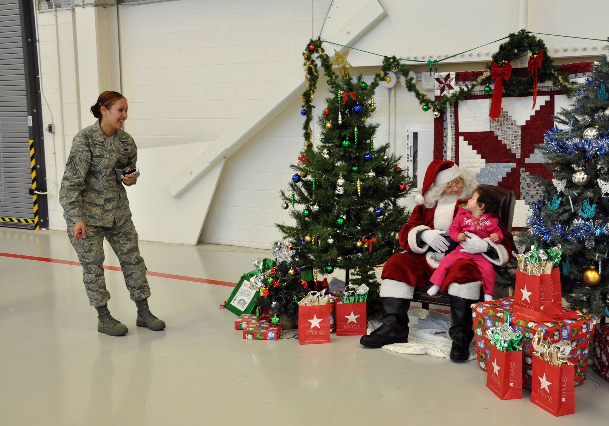 NELLIS AIR FORCE BASE, Nev. -- (Far left) Tech. Sgt. Jennifer Orozco, 926th Aircraft Maintenance Squadron Commander's Support Staff, encourages her daughter to tell Santa what she wants for Christmas at the Flanker hangar here Dec. 8. Santa's visit was part of an annual holiday party hosted by the base's Reserve and Regular Air Force maintenance units. (U.S. Air Force photo/Maj. Jessica Martin)