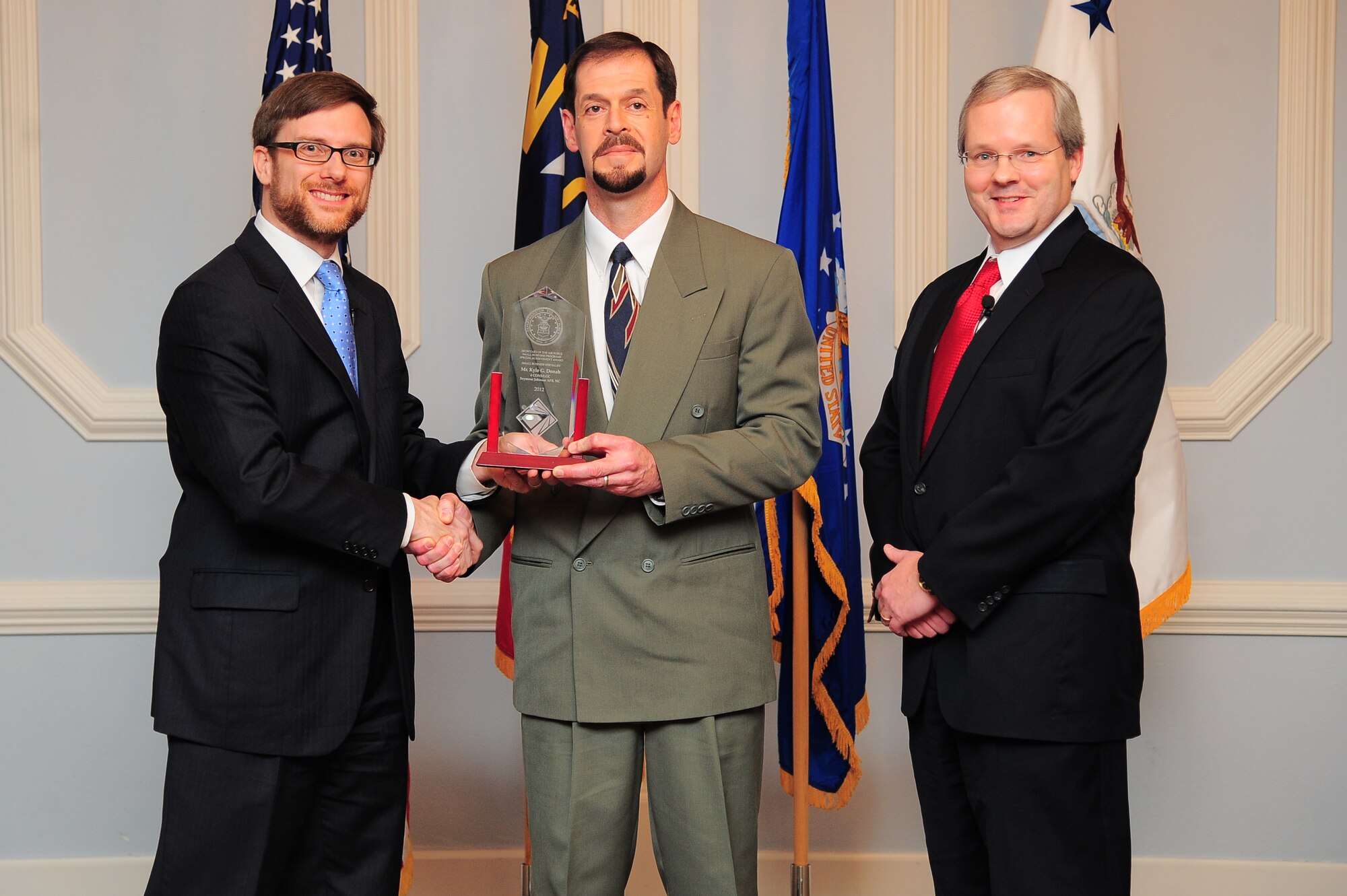 Acting Under Secretary of the Air Force Dr. Jamie Morin, and Joseph McDade, director of the Air Force Office of Small Business Programs, recognize Kyle Donah, 4th Contracting Squadron director of operations, during a small business awards ceremony on Seymour Johnson Air Force Base, N.C., Dec. 17, 2012. Donah received the 2012 Air Force Small Business Specialist of the Year award for his oversight of the runway repair and other various projects. (U.S. Air Force photo/Airman 1st Class Aubrey White/Released)