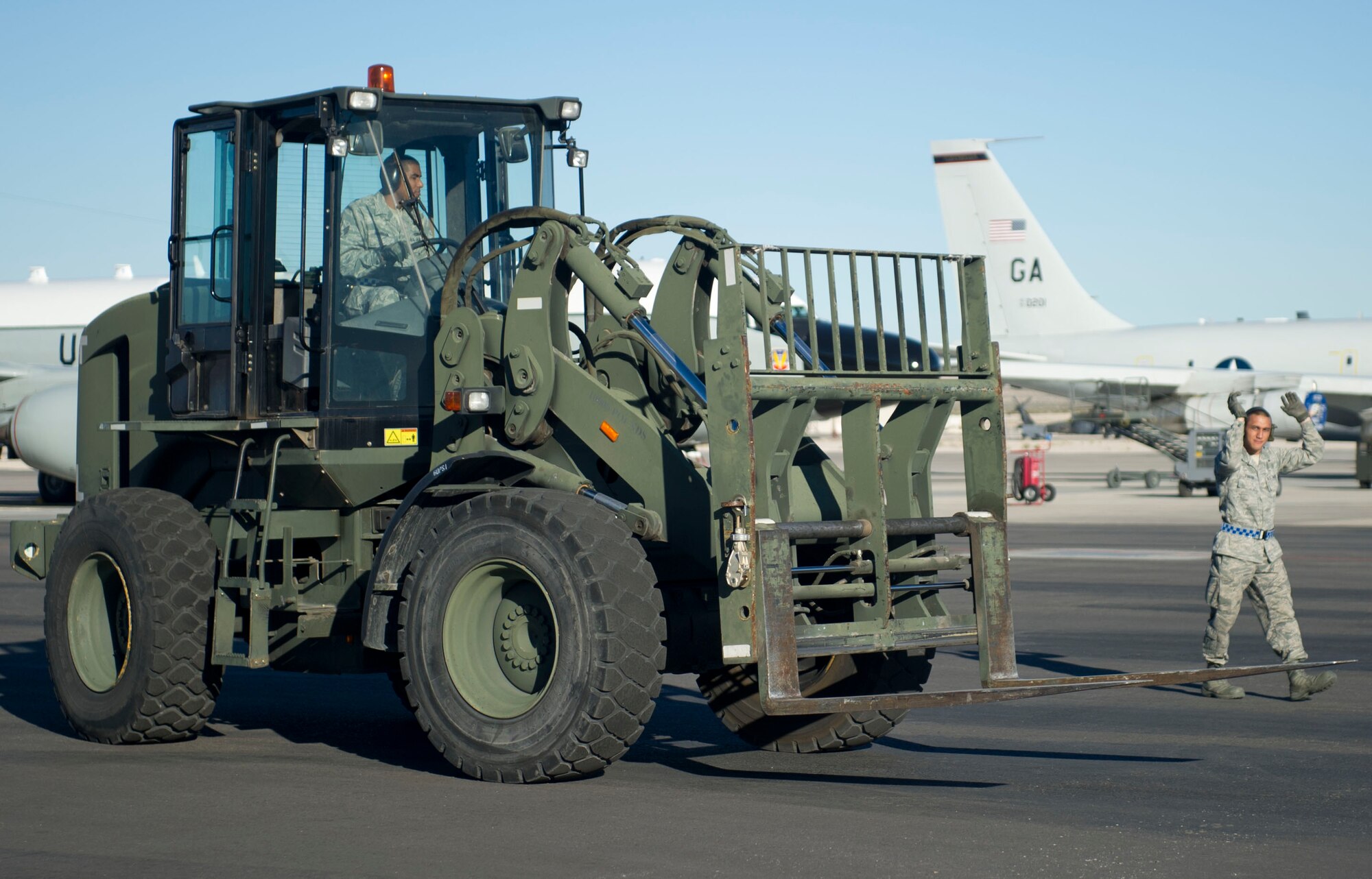 Senior Airman Cedric Harrison, 817th Global Mobility Squadron aerial port, operates a forklift as Airman 1st Class Richard Foster, 817th Global Mobility Squadron aerial port, guides him during the Mission Employment phase exercise at Nellis Air Force Base, Nev. December 5, 2012. More than 60 Airmen from the 621st Contingency Response Wing got a chance to hone their skills and help train Weapons School students. (U.S. Air Force photo by Staff Sgt. Gustavo Gonzalez)