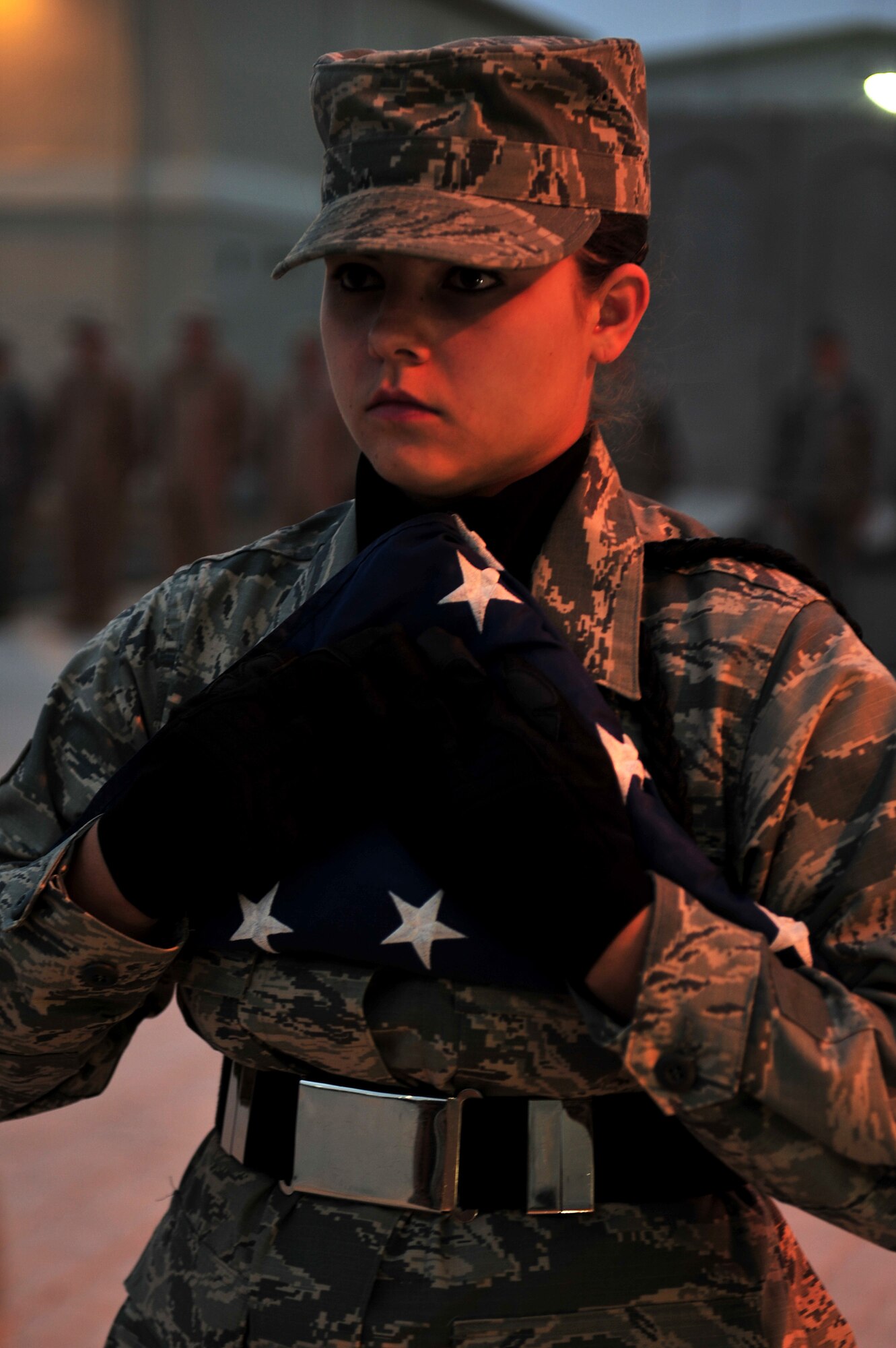 SOUTHWEST ASIA -- U.S. Air Force Airman 1st Class Alexandra Butler, 380th Expeditionary Maintenance Squadron munitions storage crew member, cradles the flag after the weekly retreat ceremony Dec. 14, 2012, at the 380th Air Expeditionary Wing in Southwest Asia. In addition to working 12-hour shifts, six days a week, Butler volunteers an additional four hours per week to base Honor Guard details and training. (U.S. Air Force photo/Tech. Sgt. Christina M. Styer) (RELEASED)