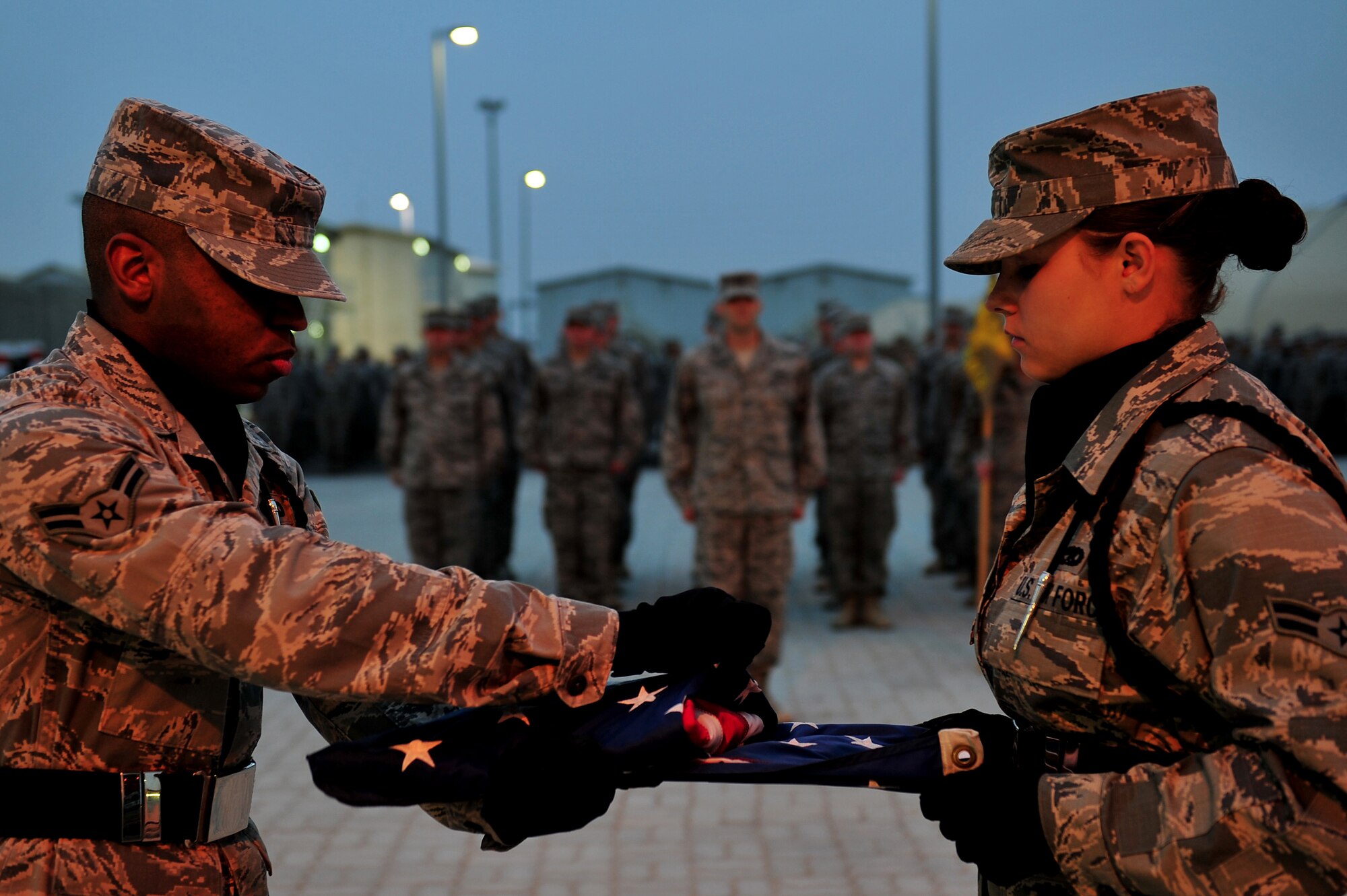 SOUTHWEST ASIA -- U.S. Air Force Airmen 1st Class Adan Rivera Castro and Alexandra Butler, 380th Expeditionary Maintenance Squadron, fold the flag during the weekly retreat ceremony Dec. 14, 2012, in Southwest Asia. Honor Guard members volunteer to serve while deployed and perform weekly and monthly retreat ceremonies, memorials and post the colors at official functions. (U.S. Air Force photo/Tech. Sgt. Christina M. Styer) (RELEASED)