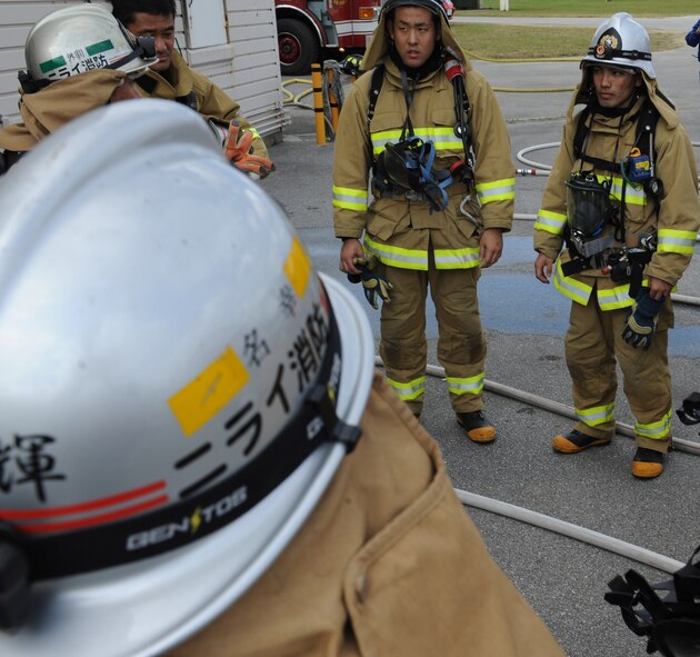 Okinawan firefighters discuss different ways to improve strategies during mutual aid live fire training on Kadena Air Base, Japan, Dec. 17, 2012. The live fire training prepared not only local firefighters for interior fire scenarios, but it also helped bring together Kadena firefighters and local fire departments different training styles in order for them to handle joint real world fires. (U.S. Air Force photo/Airman 1st Class Malia Jenkins)      