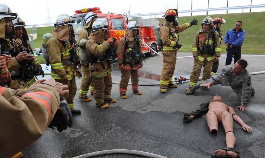 U.S. Air Force Staff Sgt. Robert Jarvis, training NCO of the 18th Civil Engineer Squadron Fire Department, shows Nirai and Okinawa City firefighter's different ways to save a victim from a burning room on Kadena Air Base, Japan, Dec. 17, 2012. Nirai and Okinawa City firefighters trained on simulated interior fire scenarios where they extinguished a kitchen fire and navigated through a building looking for victims and clearing smoke. The training also brought Nirai and Okinawa City firefighters together and the two different training styles helped prepare them for real world joint fire fighting with Kadena firefighters. (U.S. Air Force photo/Airman 1st Class Malia Jenkins)   