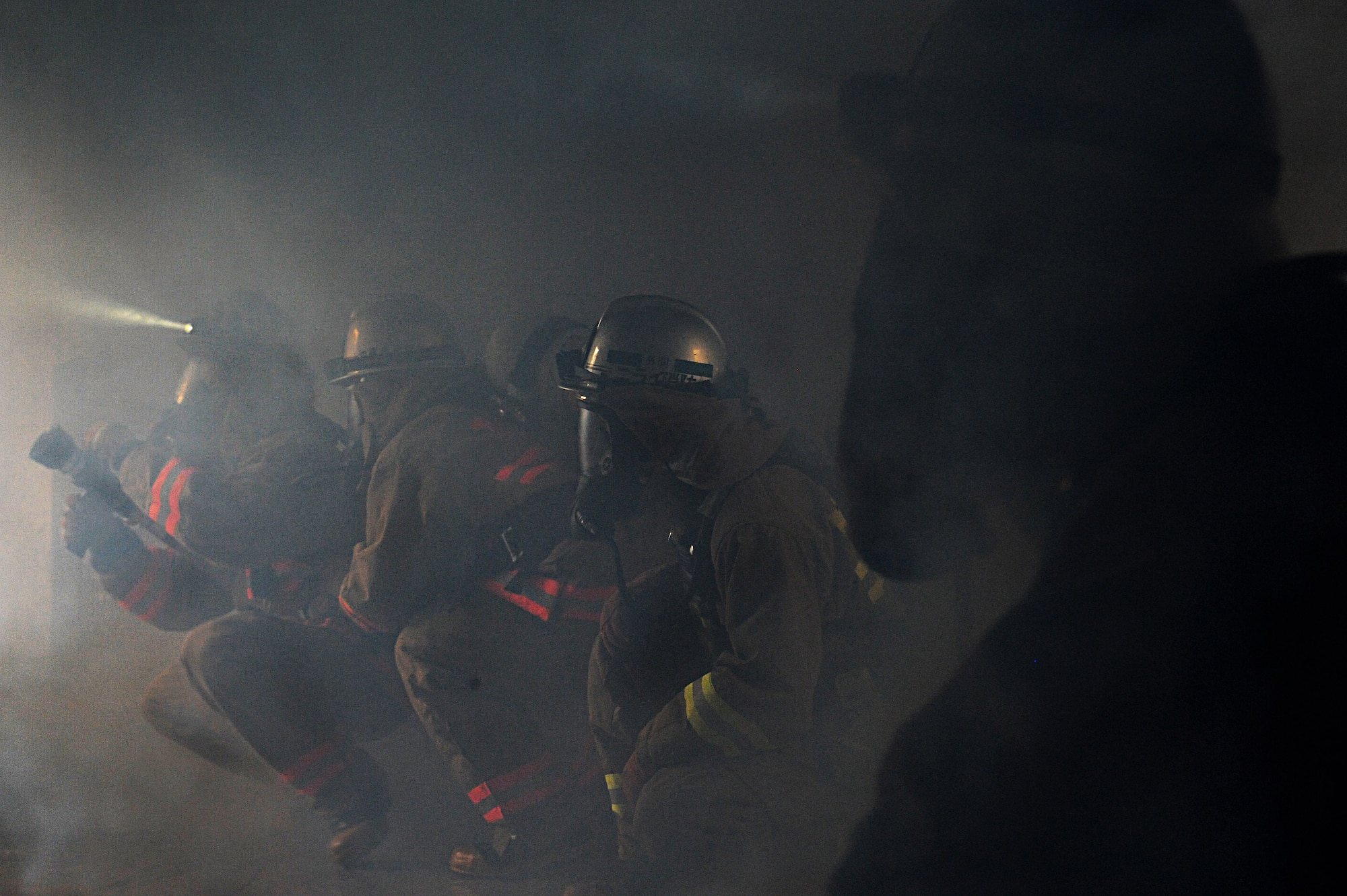 Local firefighters clear smoke from a room during a mutual aid live fire training on Kadena Air Base, Japan, Dec. 17, 2012. The live fire training prepared not only local firefighters for interior fire scenarios, but it also helped bring together Kadena firefighters and local fire departments different training styles in order for them to handle joint real world fires. (U.S. Air Force photo/Airman 1st Class Malia Jenkins)  