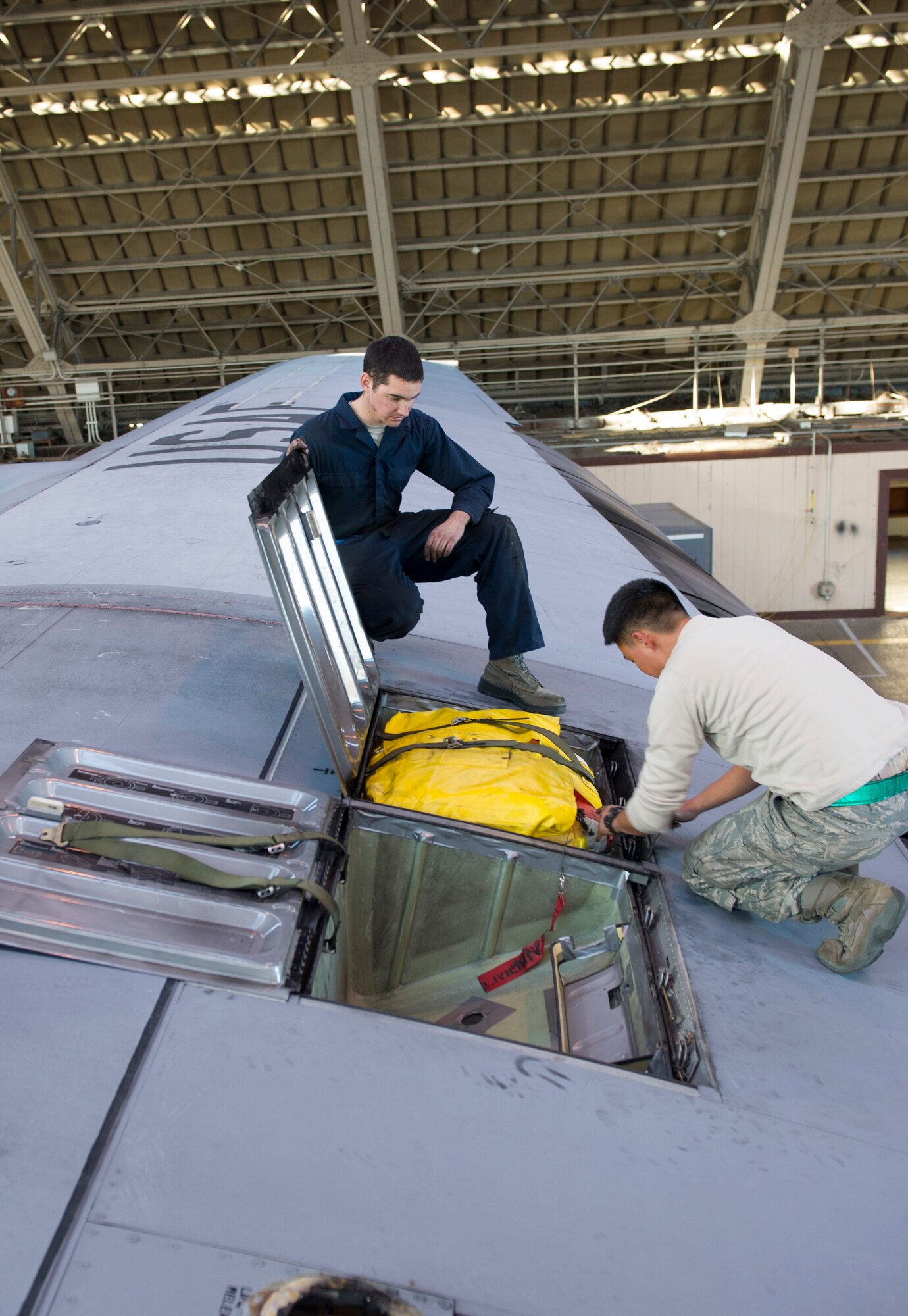 YOKOTA AIR BASE, Japan -- Airman 1st Class Neal Bentley, left, and Senior Airman Ted Choi, 374th Aircraft Maintenance Squadron crew chiefs, tie down life rafts on the wings of a C-130 Hercules aircraft at Yokota Air Base, Dec. 12, 2012. There are four life rafts on each C-130 Hercules in case the aircraft must emergency land in water. (U.S. Air Force photo by Senior Airman Andrea Salazar)