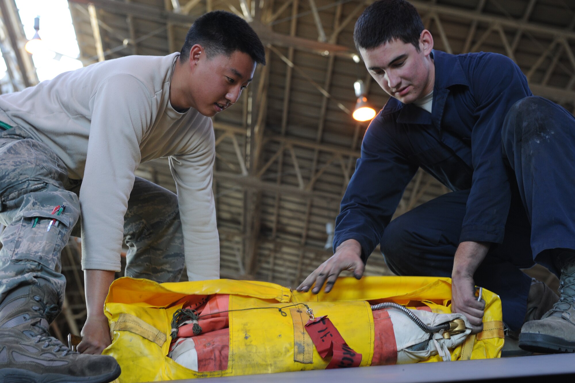 YOKOTA AIR BASE, Japan -- Senior Airman Ted Choi,left, and Airman 1st Class Neal Bentley, right, 374th Aircraft Maintenance Squadron crew chiefs, place a life raft in the wing of a C-130 Hercules aircraft at Yokota Air Base, Japan, Dec. 12, 2012. There are four life rafts on each C-130 Hercules in case the aircraft must emergency land in water. (U.S. Air Force photo by Airman 1st Class Meagan Schutter)