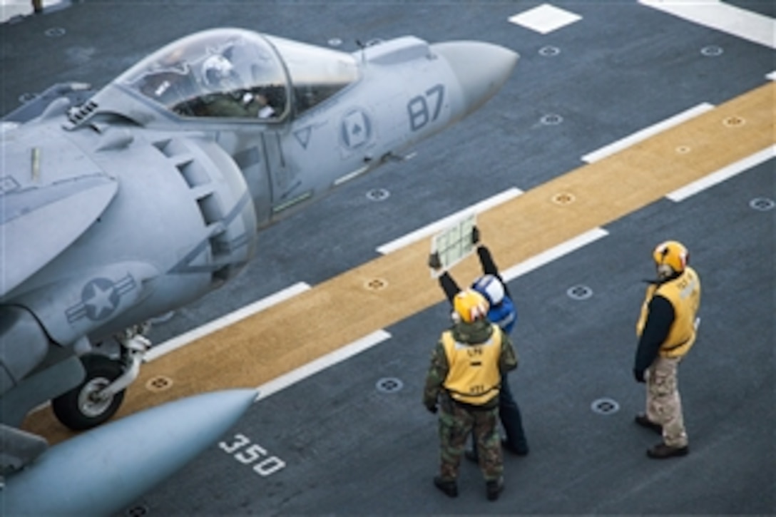 Flight deck crewmen use a status board to provide information to the pilot of an AV-8B Harrier as he prepares to takeoff from the flight deck of the USS Bataan (LHD 5) during flight operations in the Atlantic Ocean on Dec. 15, 2012.  The Harrier and pilot are assigned to Marine Medium Tiltrotor Squadron 266 as part of the embarked 26th Marine Expeditionary Unit.  