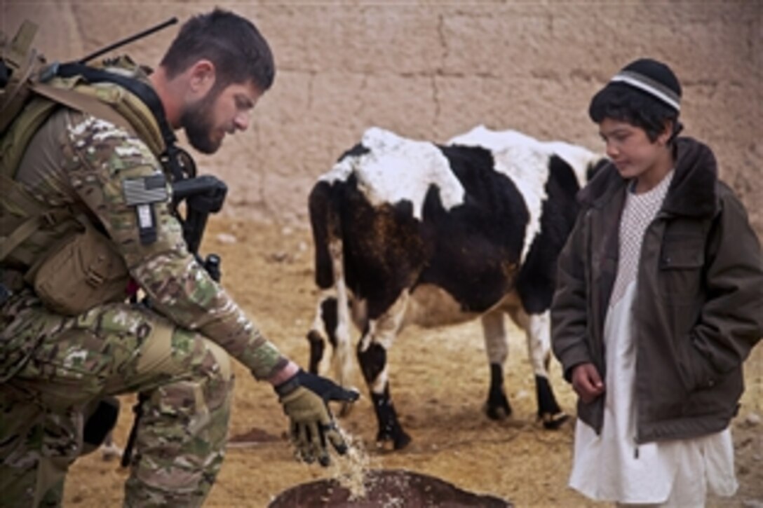 A coalition force member talks to a young villager about what to feed cattle during a patrol of  Afghanistan's Farah province, Dec. 15, 2012.