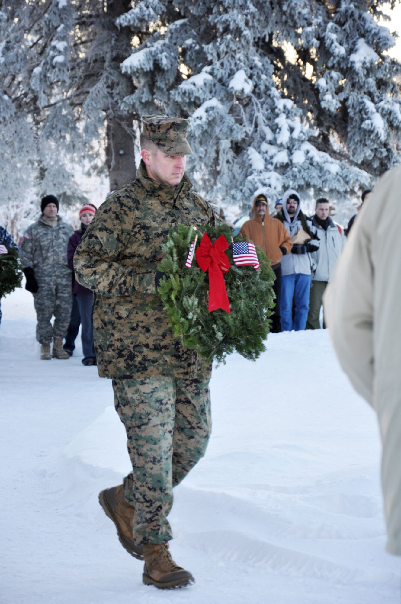 Marine Maj. Lee Johnson, the inspector-instructor for Company D, Antiterrorism 
Battalion, carries a wreath to a stand. Representatives from the Army, Marine Corps, Navy, Air Force, Coast Guard and Veterans of Foreign Wars presented wreaths and
paid their respects. The Boy Scouts, Civil Air Patrol and Alaska Military Youth
Academy, as well as military retirees and other civic organizations, also laid
wreaths.. (U.S. Air Force photos/Erin Eaton)