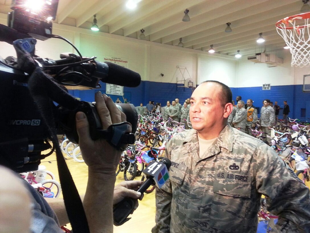 Master Sgt. Jesse Lopez gives an interview to a local news agency before distributing over 100  bikes to the Boys and Girls Clubs of San Antonio. This is the fourth consecutive year that the Alamo Wing Top Three has gathered bikes and safety equipment to donate to children in need. This years total reached 147 bikes, surpassing last years donation of 87 bikes. (U.S. Air Force photo/ Tech Sgt. Carlos J. Trevino)  