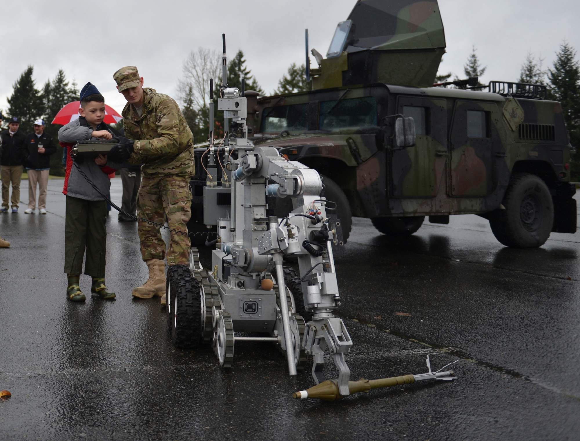 Tommy McGraw operates an explosive ordnance disposal robot with the help of Airman 1st Class Christopher Benefield, 627th Civil Engineer Squadron EOD technician, Dec. 17, 2012, at Joint Base Lewis-McChord, Wash. Tommy used the robot to pick up an inert rocket-propelled grenade. (U.S. Air Force photo/Staff Sgt. Jason Truskowski)