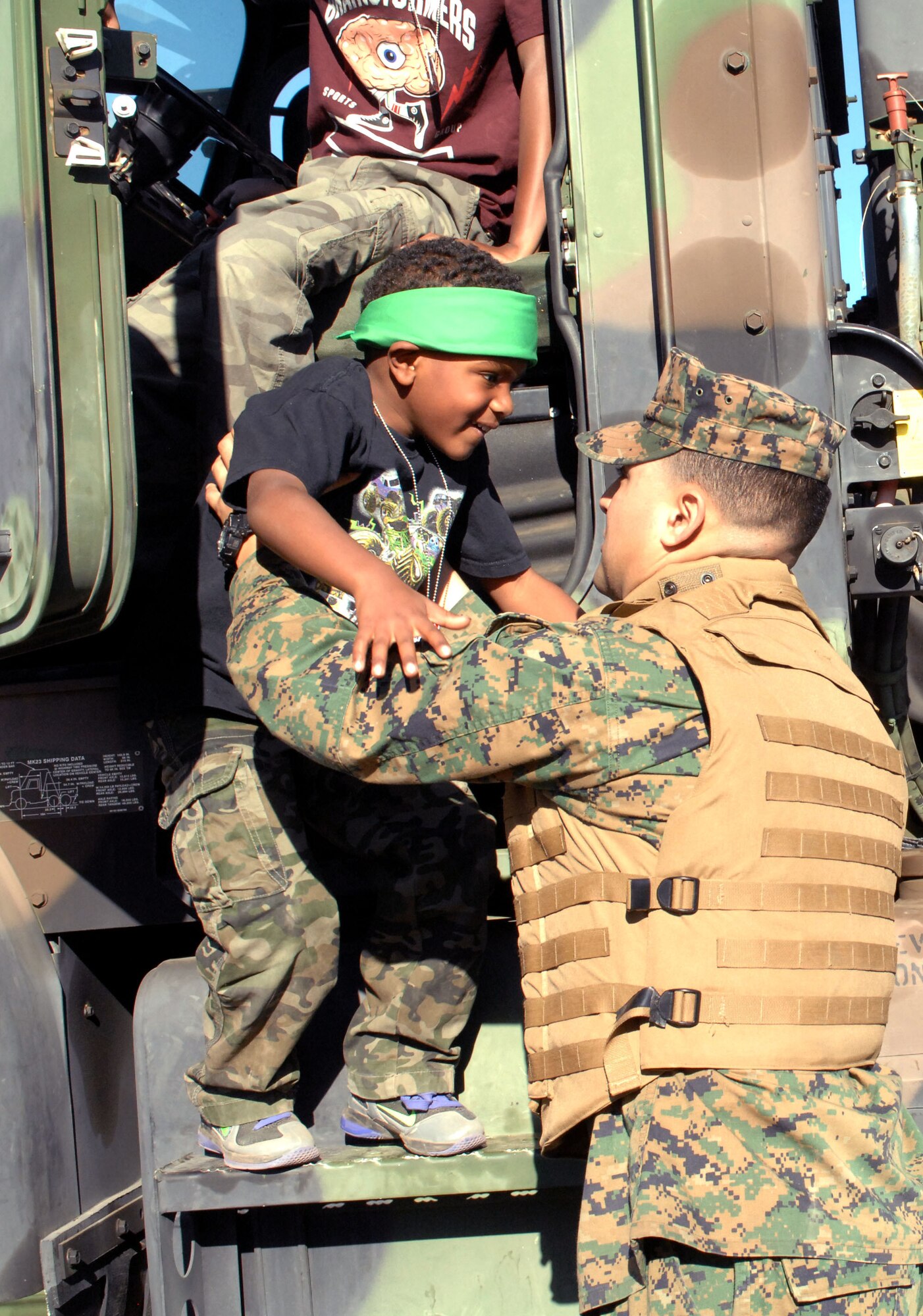 Devin Winston, son of U.S. Air Force Tech Sgt. Earnest Winston, 12th Air Force Air Forces Southern, and Tech Sgt. Jessica Winston, 355th Force Support Squadron, enlists the aid of a U.S. Marine as he exits a government vehicle after sitting in the driver's seat during the "Boot On Boots Off" event held on Davis-Monthan Air Force Base, Ariz., Dec. 10, 2012. In addition to touring the trucks, children learned how to stand in formation and ran an obstacle course.