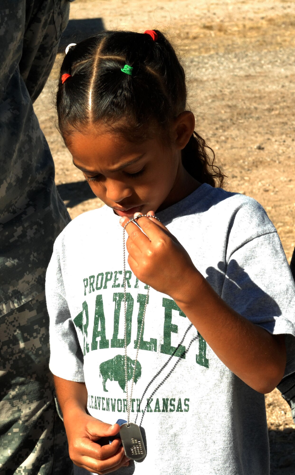 Marissa Daniels, daughter of U.S. Army Lt. Col. Tony Daniels, 1st Battlefield Coordination Detachment, inspects the dog tags she received while "inprocessing" during the "Boot On Boots Off" event held on Davis-Monthan Air Force Base, Ariz., Dec. 10, 2012. Upon arrival, children were led through a processing line where they received items such as backpacks, water bottles and "immunizations" which were candy shots and pills.