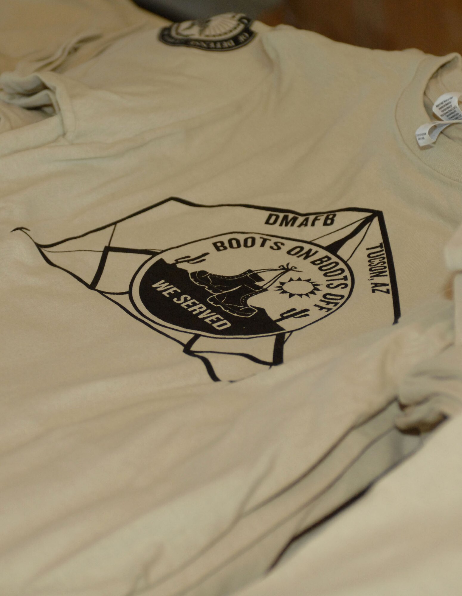 Children of military parents received a souvenir t-shirt when they inprocessed during the "Boot On Boots Off" event held on Davis-Monthan Air Force Base, Ariz., Dec. 10, 2012. "Boot On Boots Off" was a joint effort between D-M, the Tucson Naval Reserve Center and the local chapter of Operation Military Kids. Children participated in a mock deployment designed to give them insight into what their parents experience during real-world deployments.