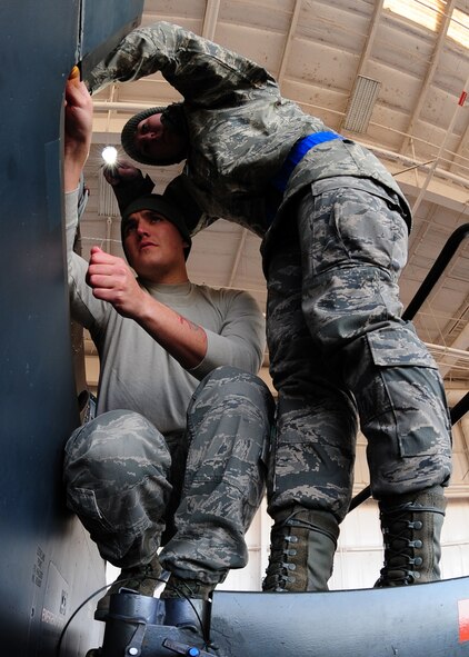 Senior Airman Shane Robison, 9th Aircraft Maintenance Squadron crew chief, checks the work of Airman 1st Class Tylher Whaley as she illuminates the interior of an Air Force RQ-4 Global Hawk intelligence, surveillance and reconnaissance aircraft Dec. 19, 2012, at Beale Air Force Base, Calif. Crew chiefs re-assembled the aircraft after it underwent maintenance. (U.S. Air Force photo by Senior Airman Shawn Nickel/Released)