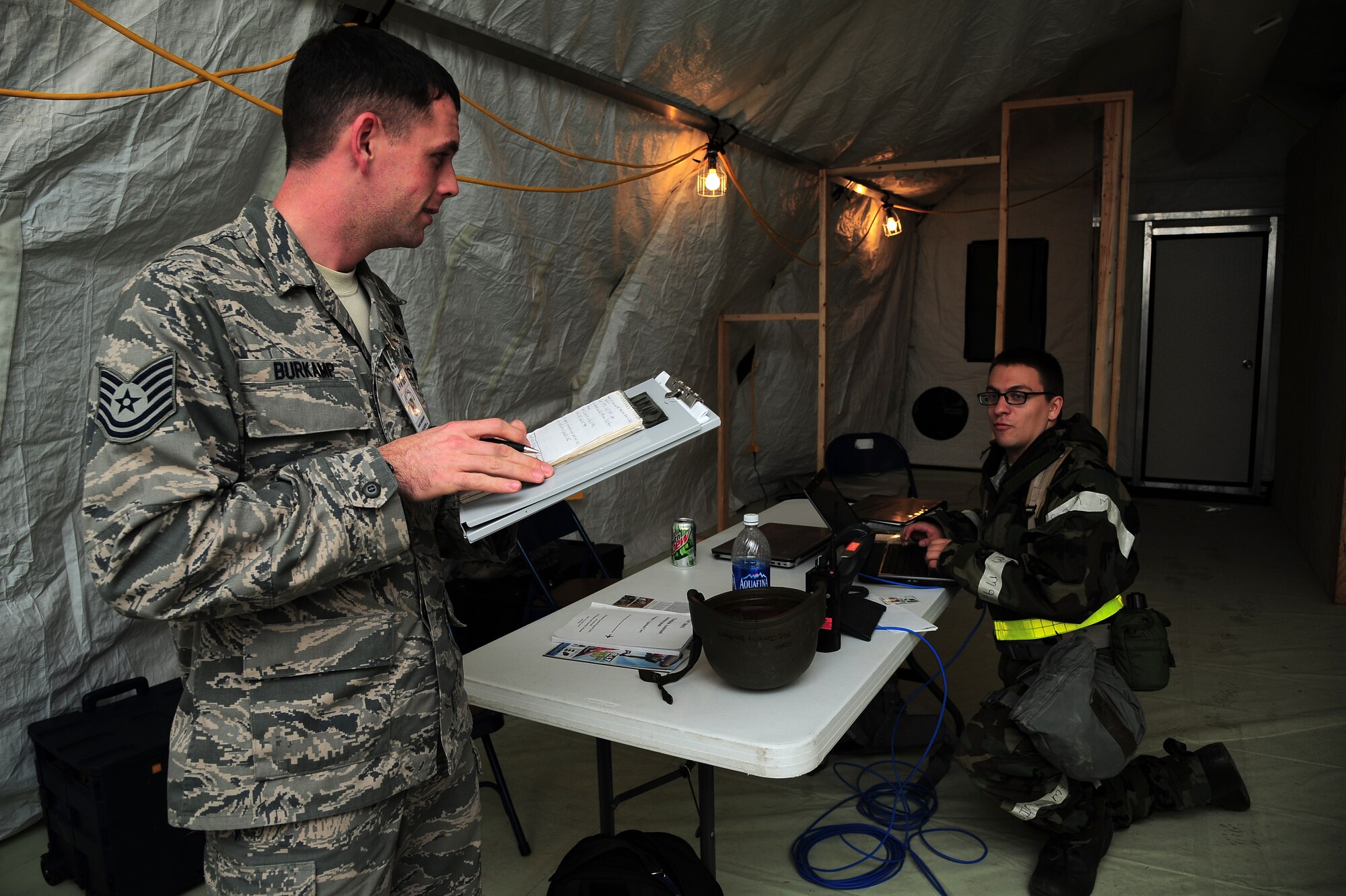 U.S. Air Force Tech. Sgt. David Burkamp, 4th Communications Squadron asset manager, questions Airman 1st Class Jeremy Brothers during Operational Readiness Exercise Coronet Warrior 12-06, at a simulated deployed location on Seymour Johnson Air Force Base, N.C., Dec. 18, 2012. Brothers was evaluated on his ability to provide communications support during varying force protection condition levels and mission oriented protective postures. (U.S. Air Force photo/Airman 1st Class Aubrey White/Released)