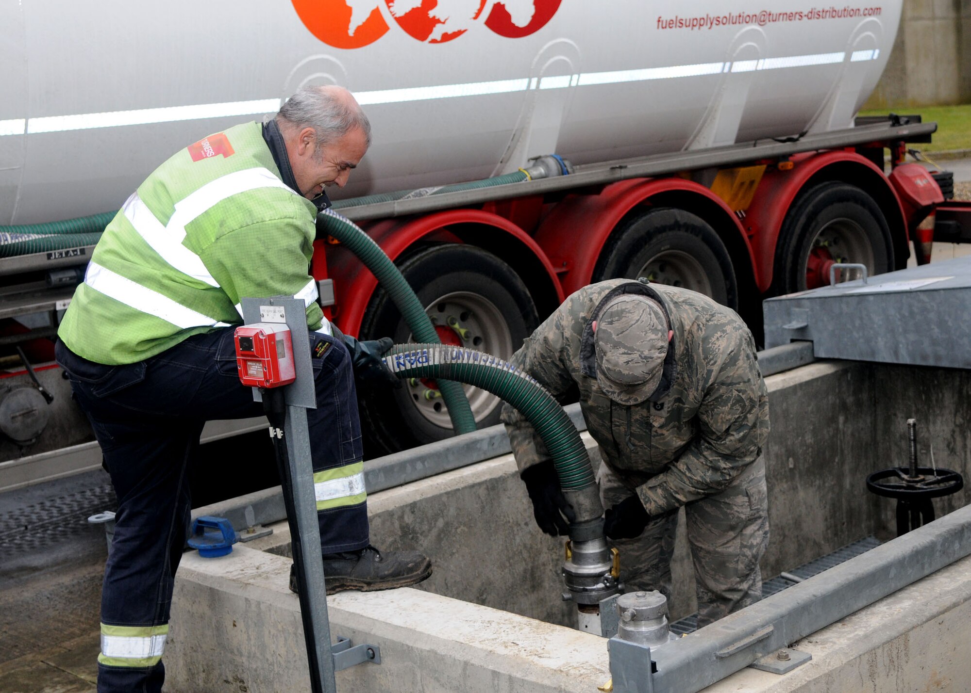 Tech. Sgt. Eric Wise, 100th Civil Engineer Squadron, NCO in-charge fuels systems maintenance from Dakota Ill.,(right) and John Callaghan, contractor,  connect the fuel pipe from the  truck to the underground pump Dec. 19, 2012 at RAF Mildenhall. (U.S. Air Force photo by Airman 1st Class Kelsey Waters/Released)