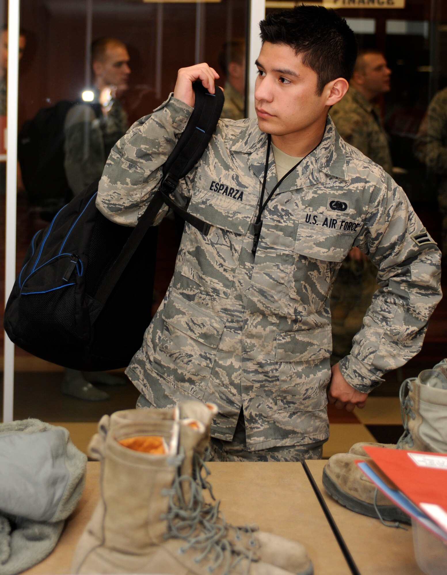 Airman 1st Class Kristopher Esparza, 28th Logistics Readiness Squadron Aircraft Parts Store technician, dons his backpack after it was X-rayed during a deployment readiness exercise at the Deployment Center on Ellsworth Air Force Base, S.D., Dec. 14, 2012. Esparza was one of approximately 164 Airmen who participated in the exercise hosted by the 28th LRS. (U.S. Air Force photo by Airman Ashley J. Woolridge/Released) 