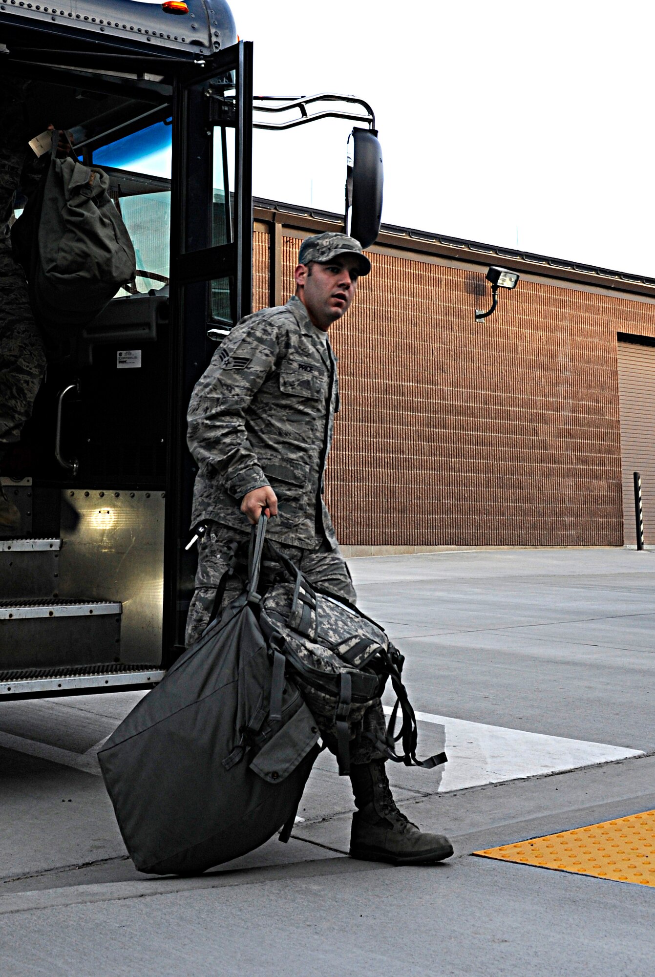Senior Airman Alex Price, 28th Civil Engineer Squadron electrical systems technician, exits a bus during a 28th Mission Support Group deployment readiness exercise outside the Deployment Center at Ellsworth Air Force Base, S.D., Dec. 14, 2012. The 28th MSG conducts monthly exercises to ensure its Airmen are in a constant state of combat readiness. (U.S. Air Force photo by Airman Ashley J. Woolridge/Released) 
