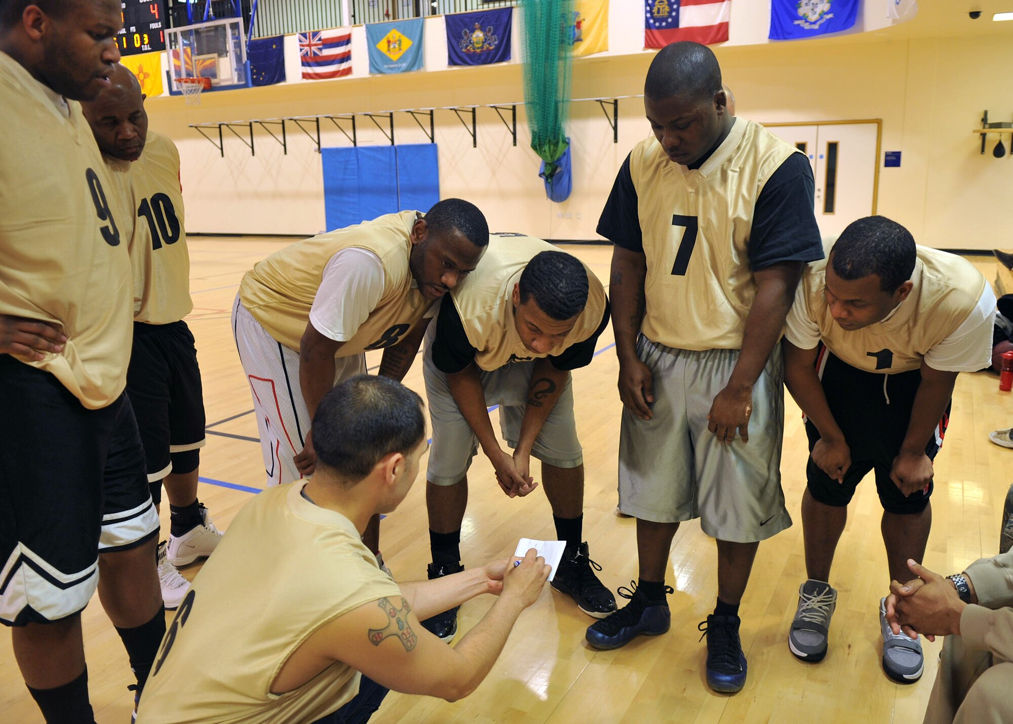 Players of the 100th Communications Squadron come together in a huddle during a basketball game against the 100th Security Forces Squadron Dec. 18, 2012, at the Hardstand Fitness Center at RAF Mildenhall, England. The 100th SFS won the game edging the 100th CS 54-37. (U.S. Air Force photo by Senior Airman Jerilyn Quintanilla/Released)