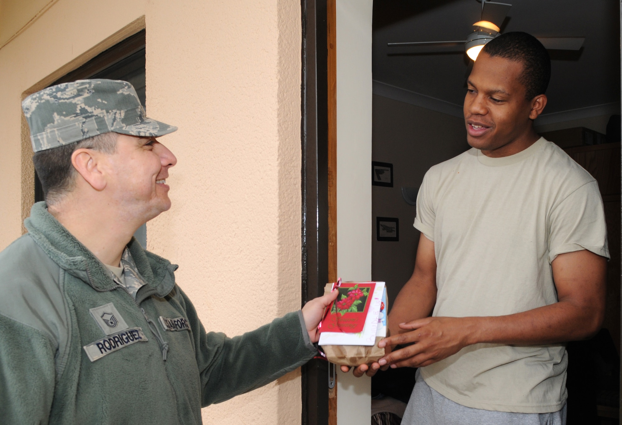 Master Sgt. Robert Rodriguez, 67th Special Operations Squadron first sergeant, delivers a bag of cookies to Airman 1st Class Jelandy Rozier, 67th SOS, Dec. 19, 2012, at RAF Mildenhall, England. Children from the RAF Mildenhall Child Development Center and RAF Mildenhall Youth Center decorated the cookie bags for the Airmen. (U.S. Air Force photo by Senior Airman Rachel Waller/Released) 