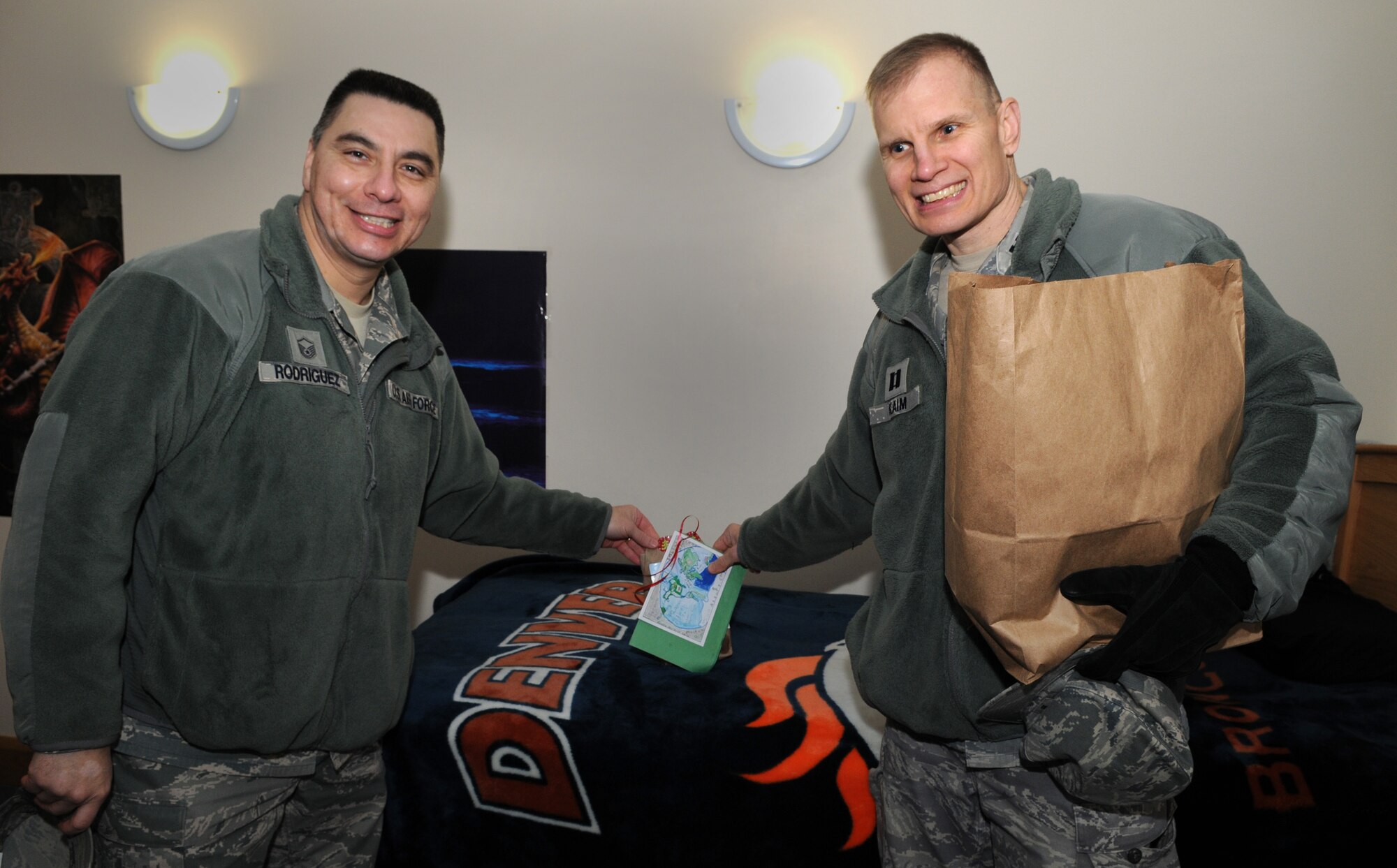 Master Sgt. Robert Rodriguez, 67th Special Operations Squadron first sergeant, and Father (Capt.) Phillip Kaim, 100th Air Refueling Wing chaplain, leave cookies for a 67th SOS Airman Dec. 19, 2012, at RAF Mildenhall, England. Team Mildenhall first sergeants delivered bags of cookies to unaccompanied Airmen living in the dorms here to wish them a Happy Holidays. (U.S. Air Force photo by Senior Airman Rachel Waller/Released) 